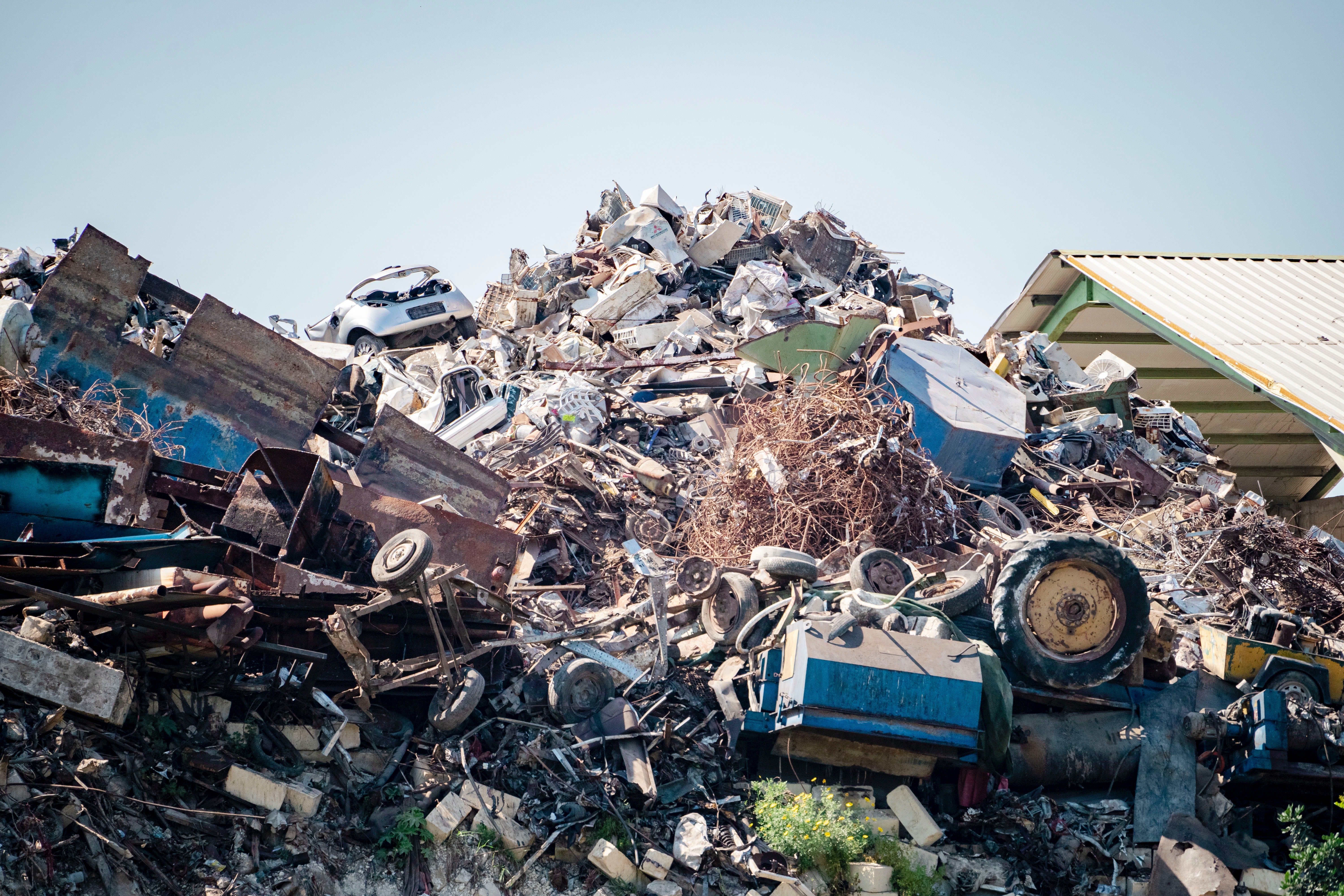 A garbage pile containing old cars and mechanical equipment.