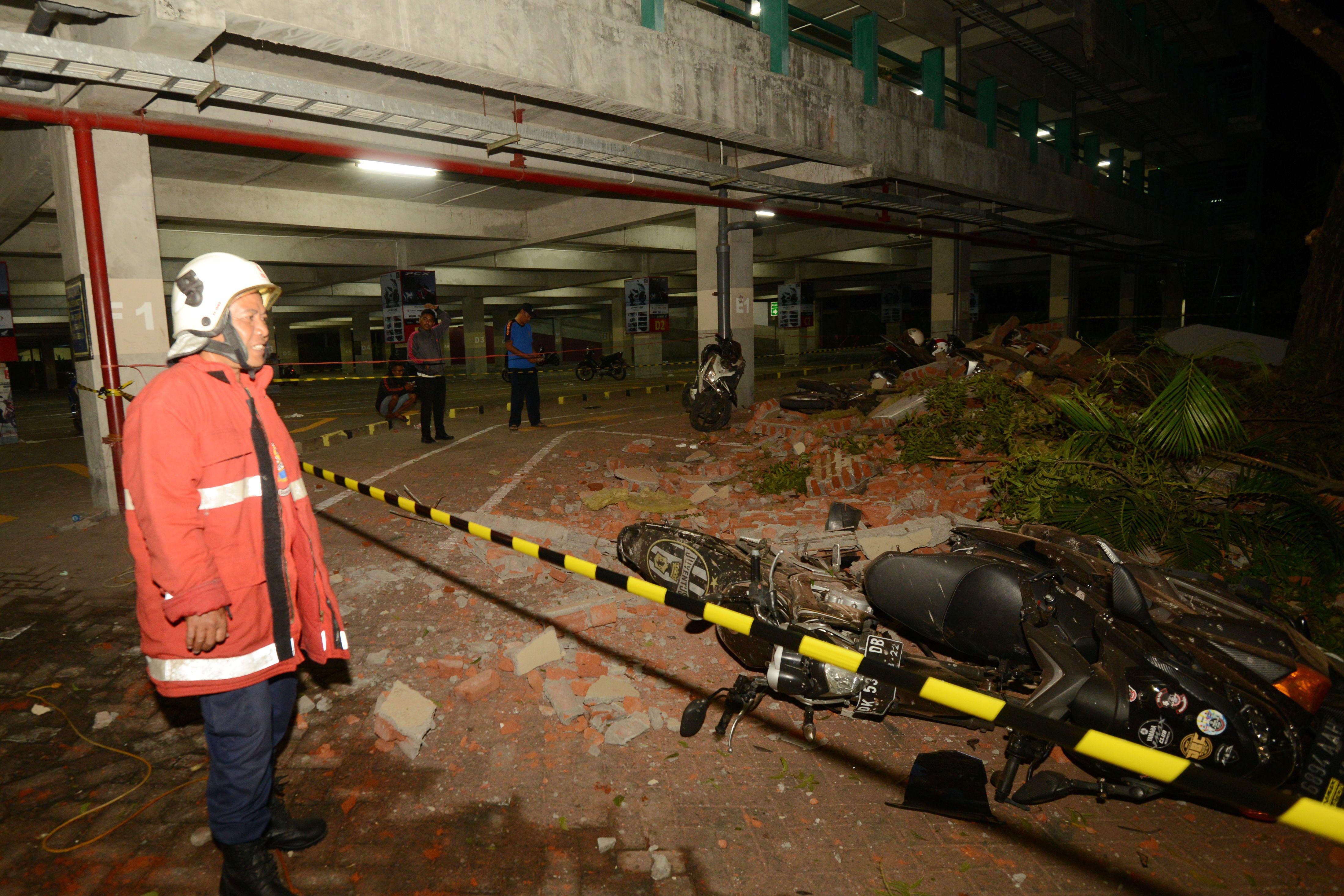 Rescue personnel stands next to a motorcycle that fell down at a mall in Bali's capital Denpasar on August 5, 2018 after a major earthquake rocked neighboring Lombok island. 