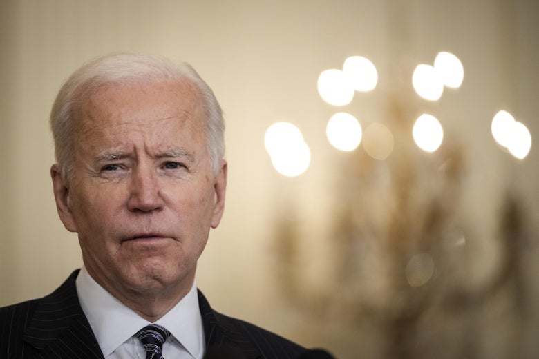 Joe Biden standing with a chandelier in the background