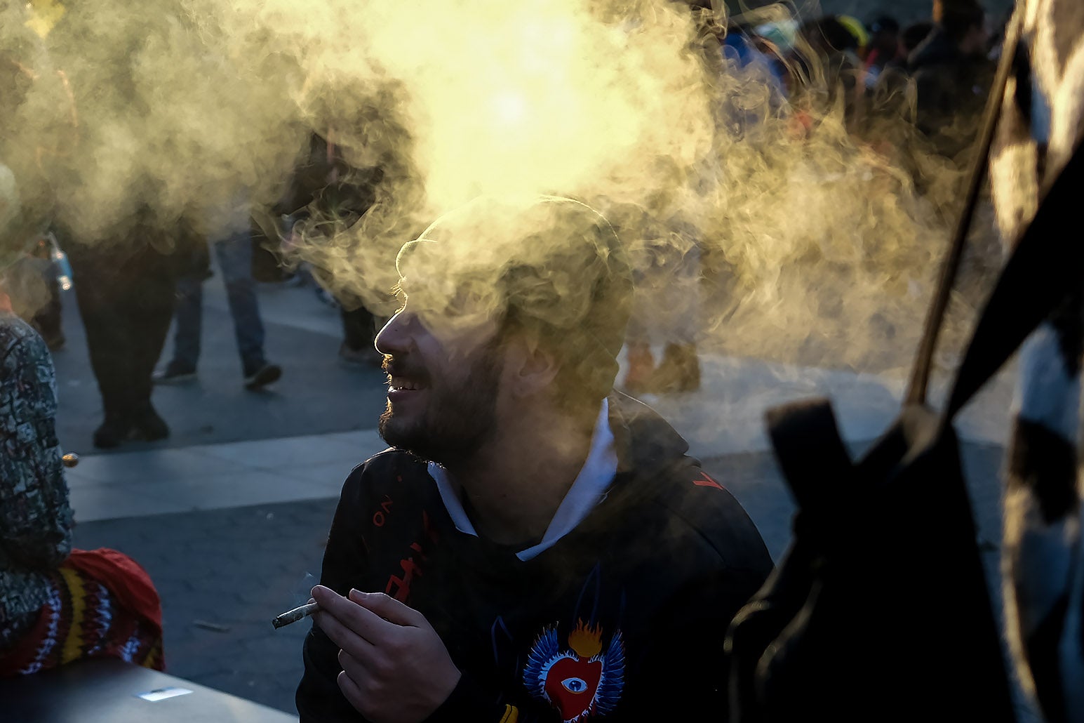 A man smokes a joint and clouds of smoke surround his head. 
