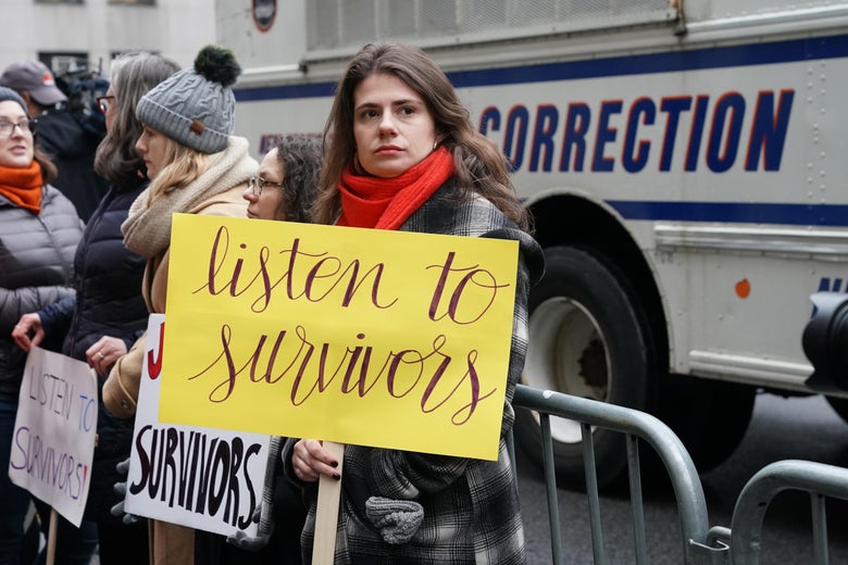 A woman holds a sign that says "listen to survivors" standing outside the courthouse on the first day of Harvey Weinstein's trial.