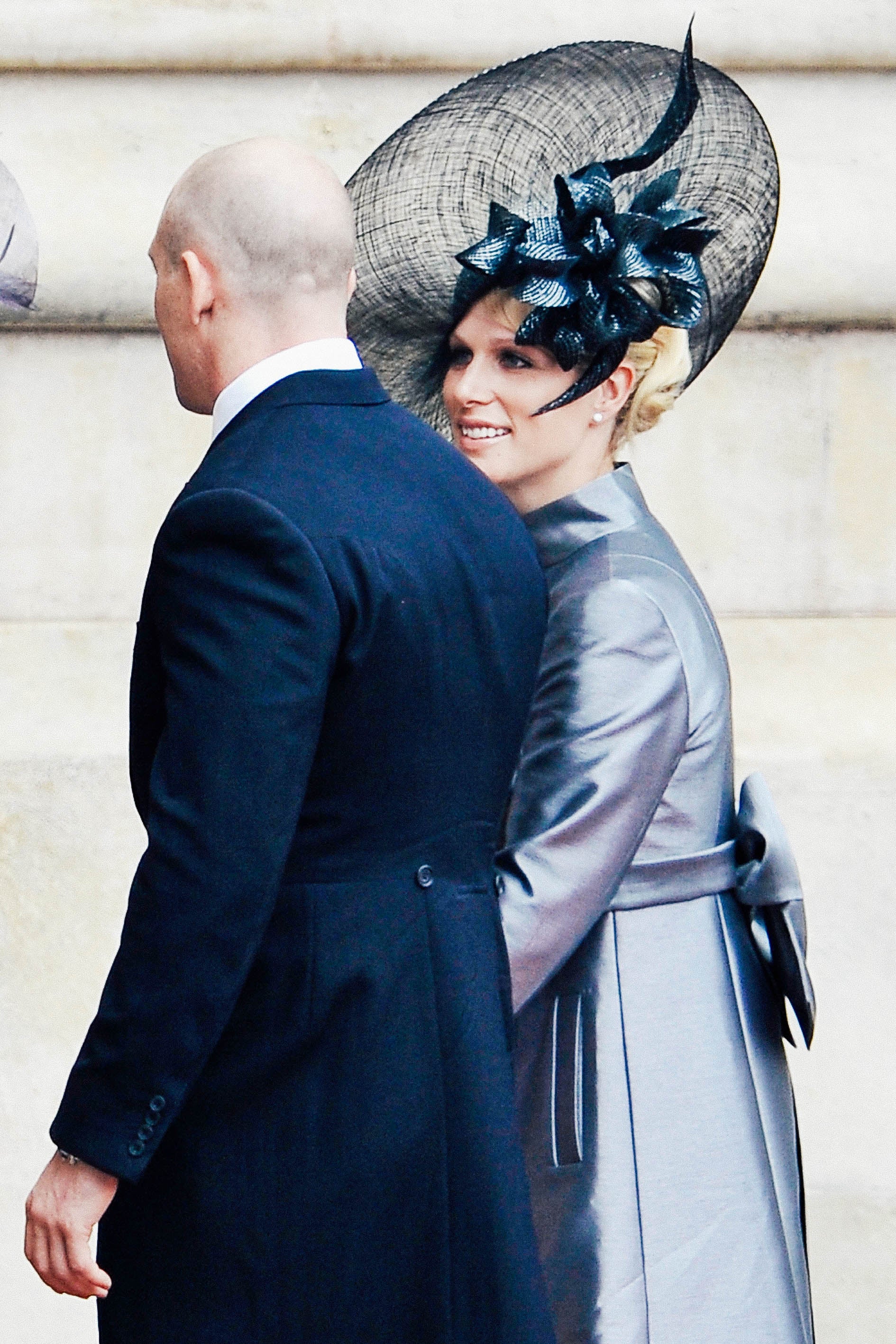 Zara Phillips wears a silver dress and elaborate black-silver hat.