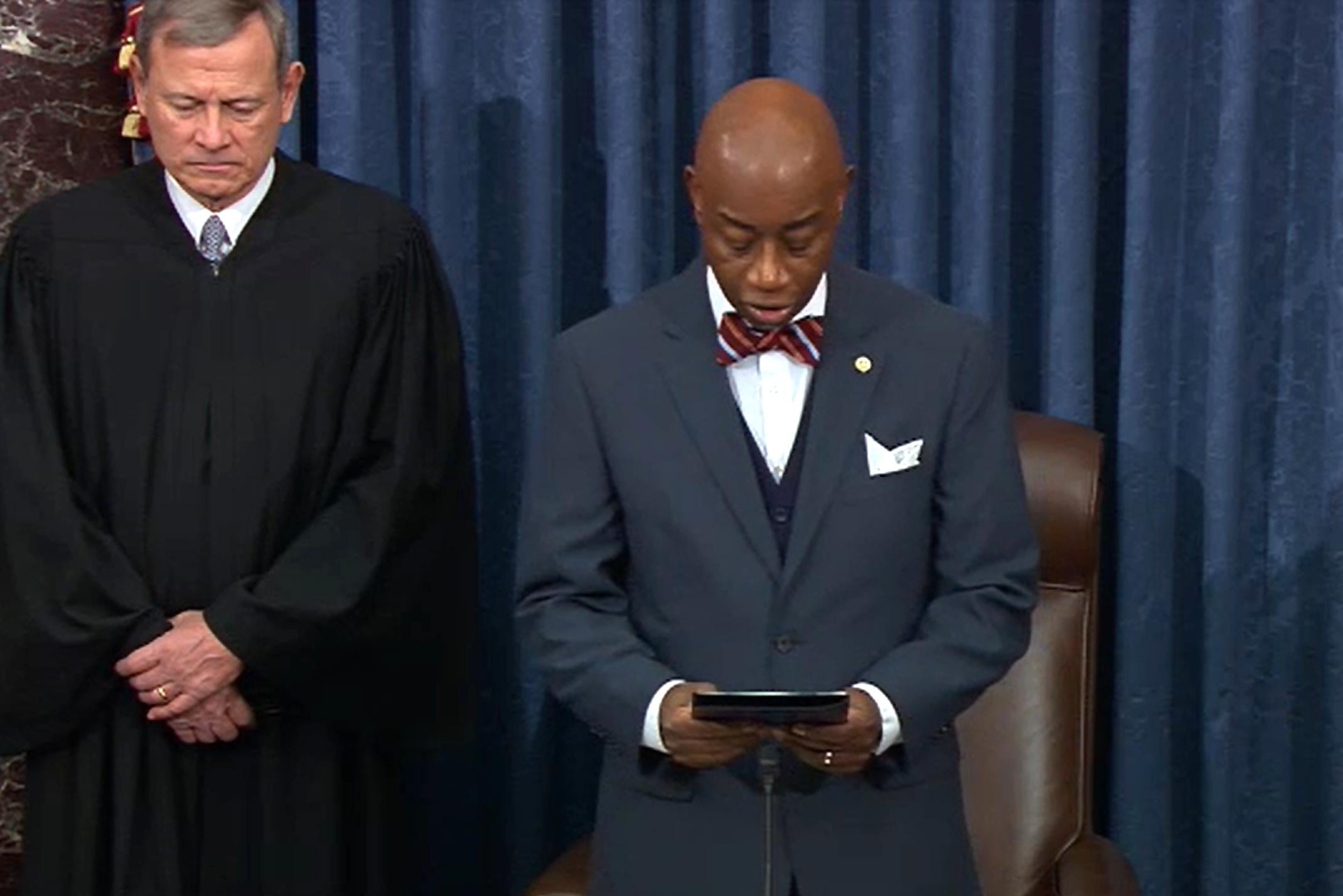 Roberts bows his head as Black reads from a book.