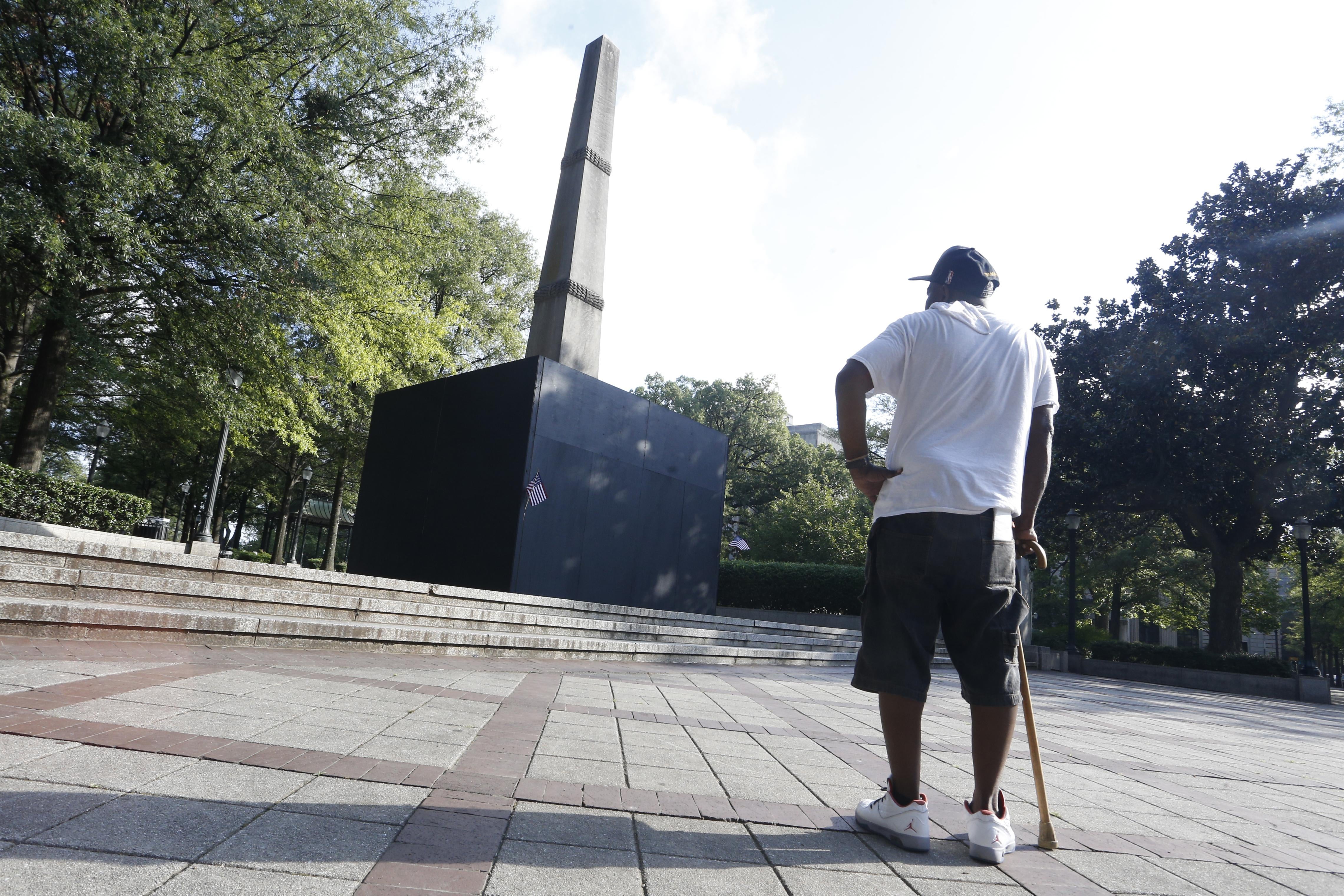 A man with a cane pauses to look at a now covered confederate monument in Linn Park in Birmingham, Alabama.