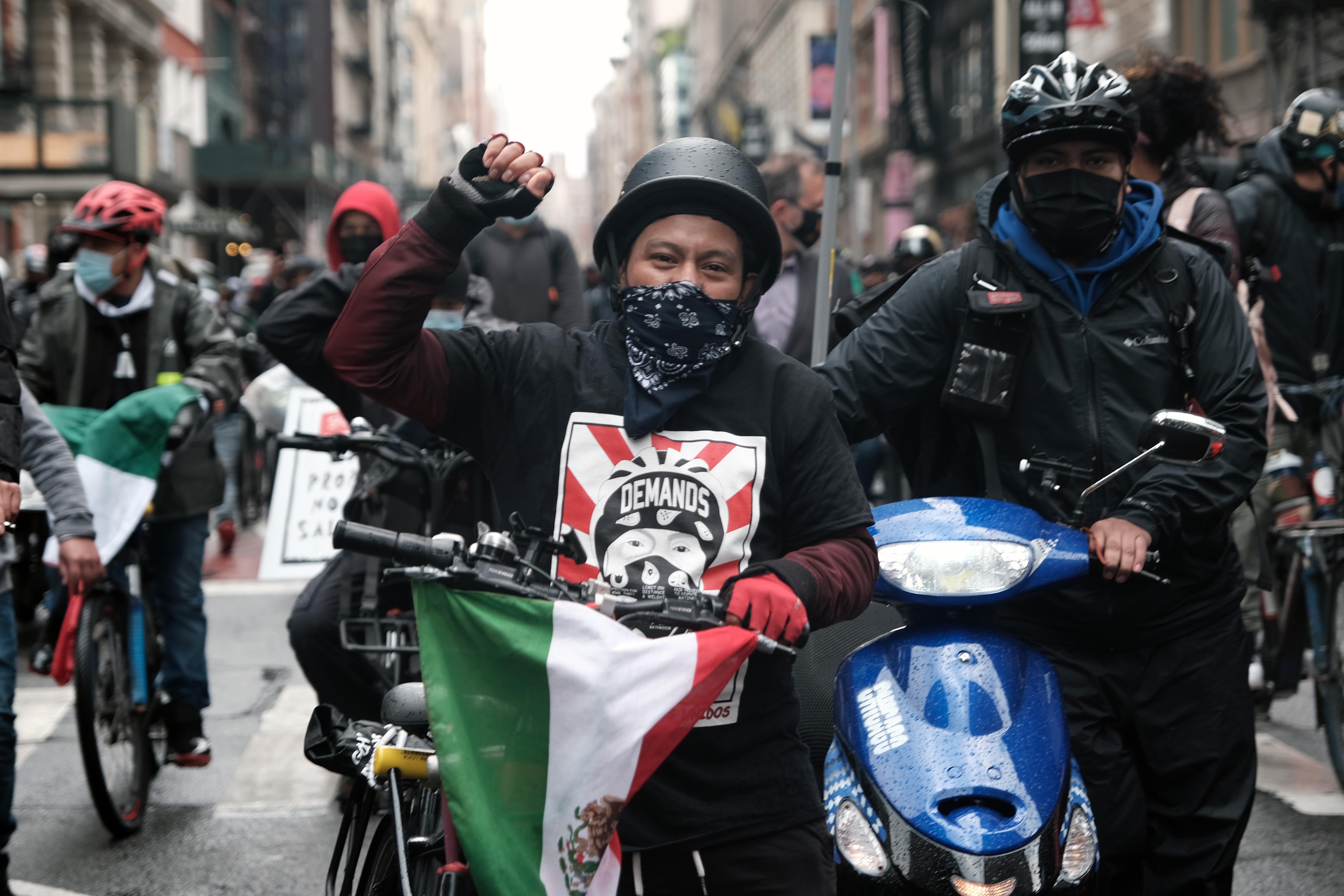 A man on a bike raises his fist in a march down a city street