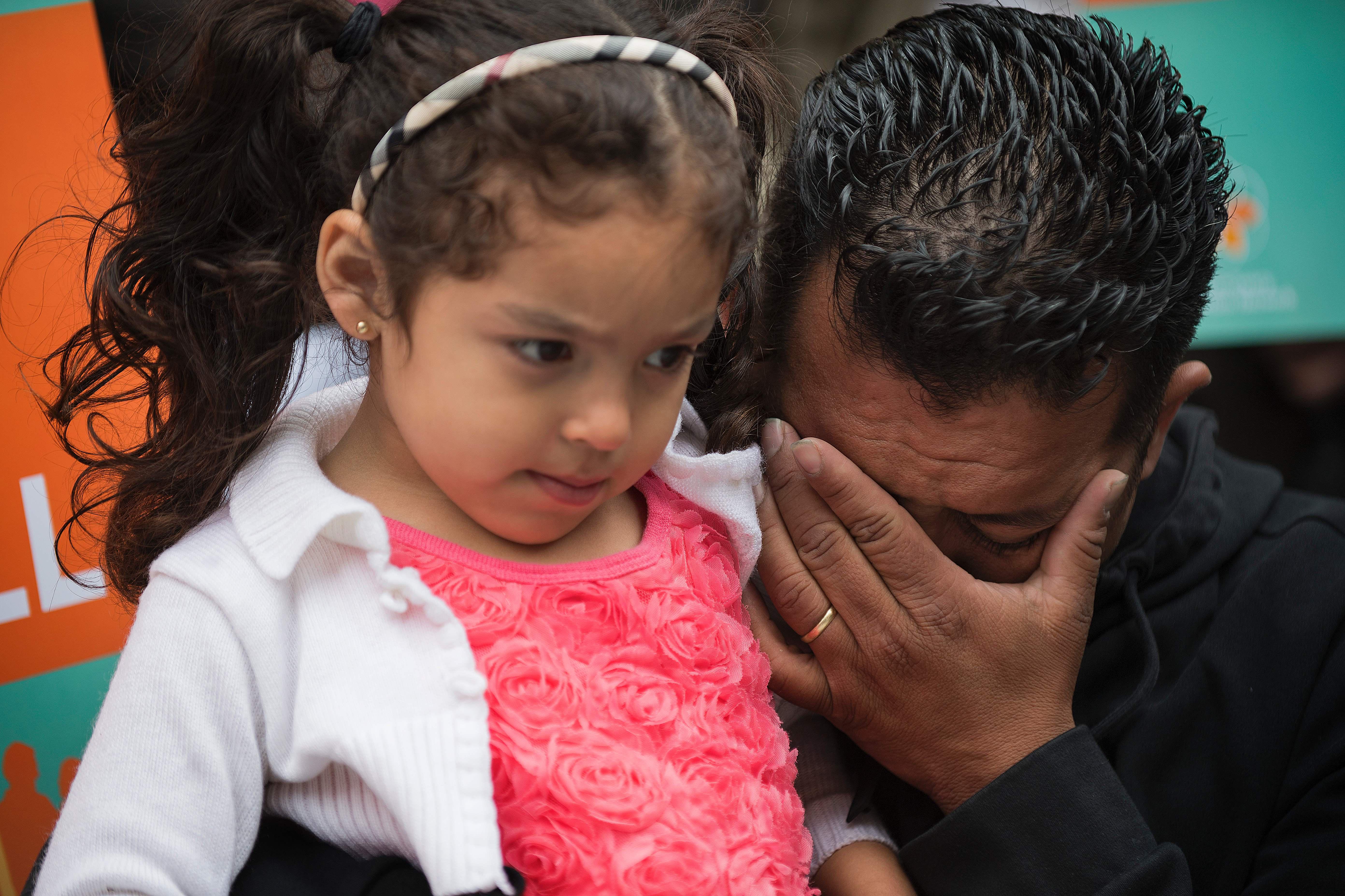 From right, Rene Bermudez wipes away tears as he holds his 4-year-old daughter Danyca during a protest on behalf of his wife Liliana Cruz Mendez on May 23.