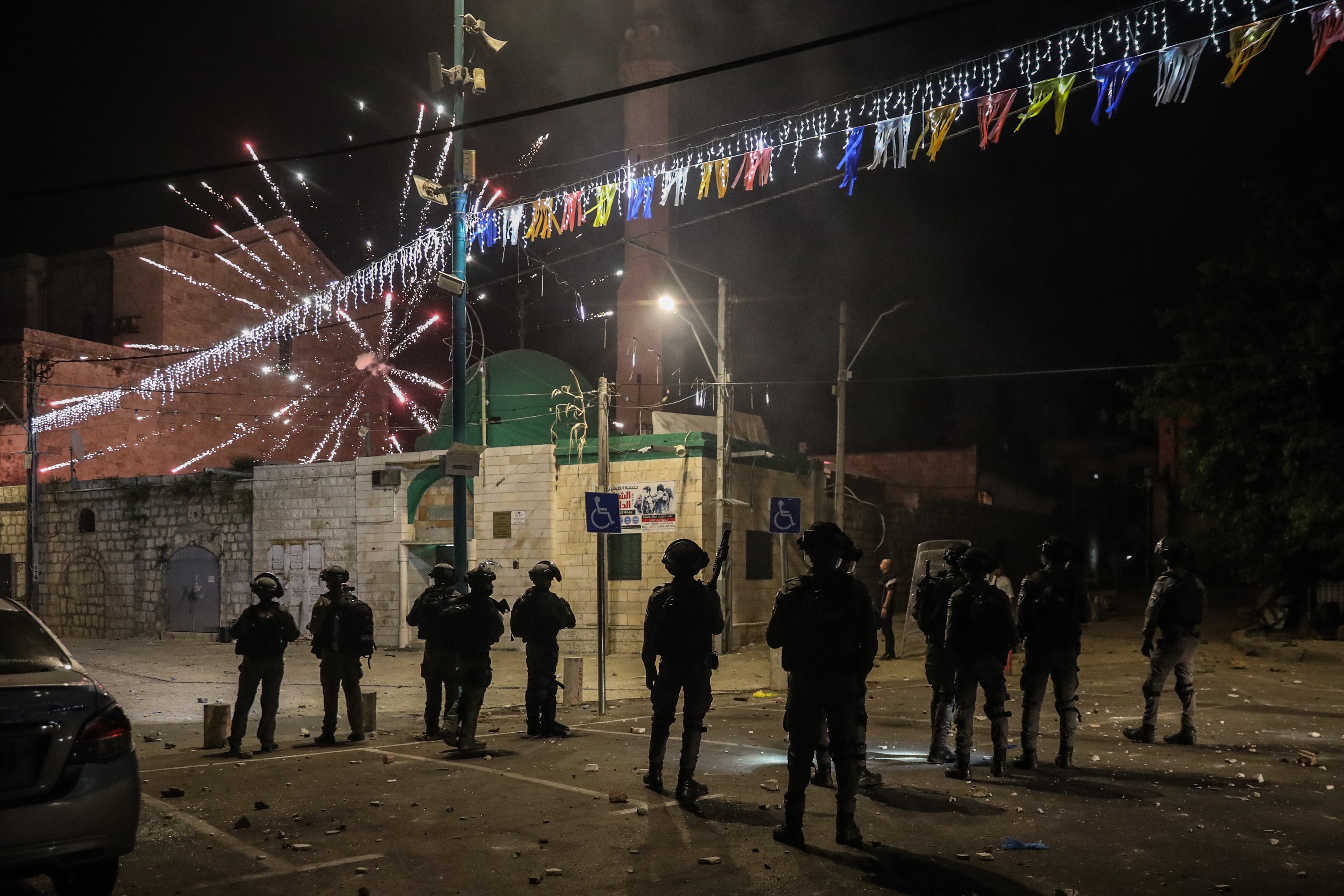 Fireworks are released towards Israeli soldiers standing in a parking lot during clashes amid a night-time curfew.