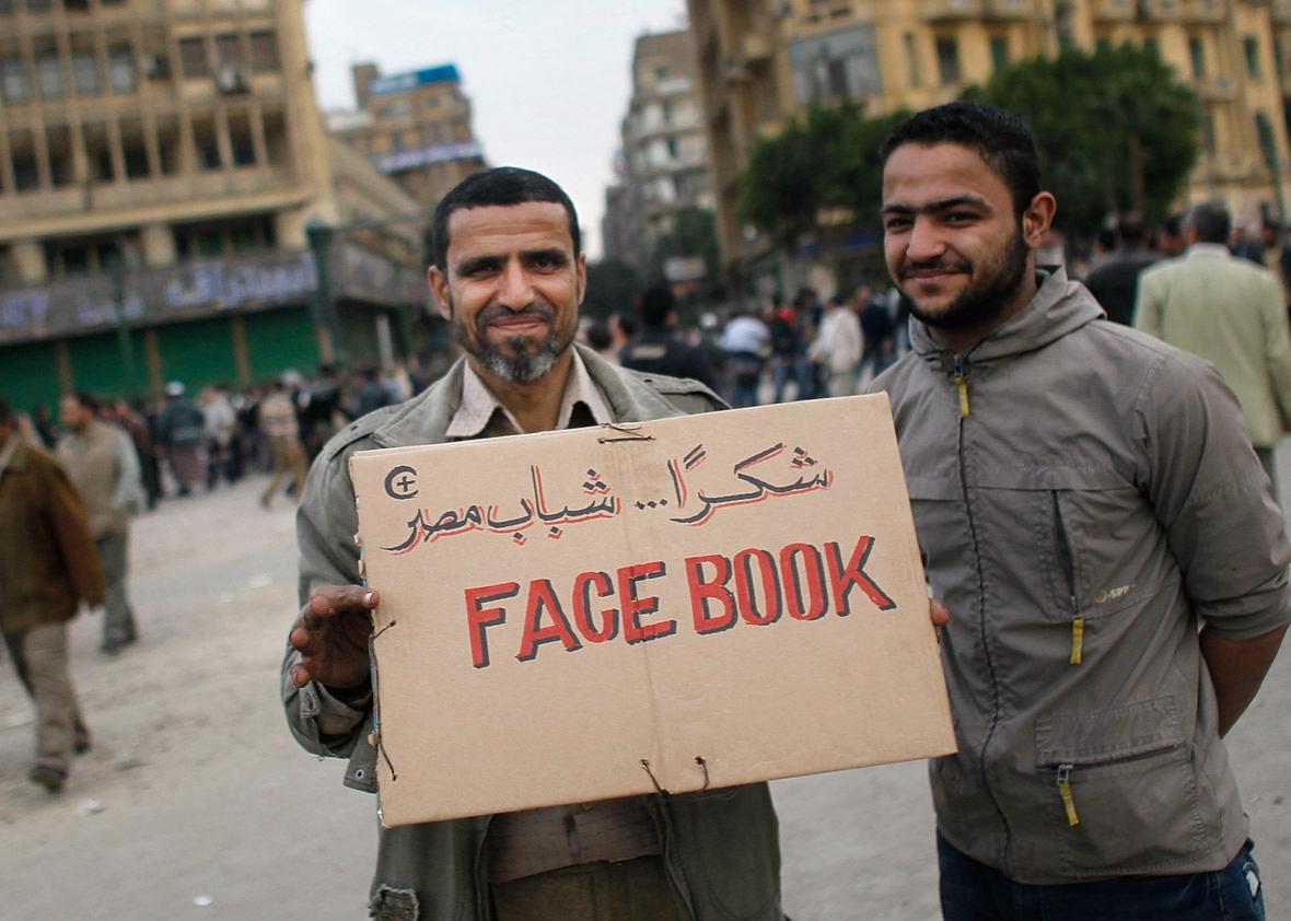 Anti-government protesters hold a sign referencing the Facebook social networking website that has been important in organizing protesters in Tahrir Square 