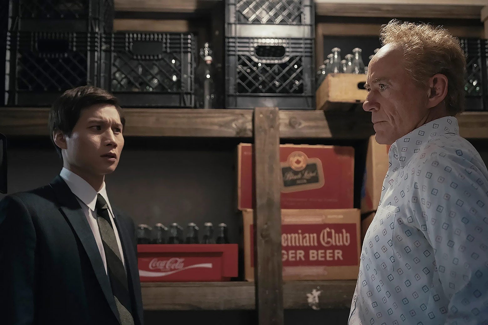 Two men talk seriously in a storage room.