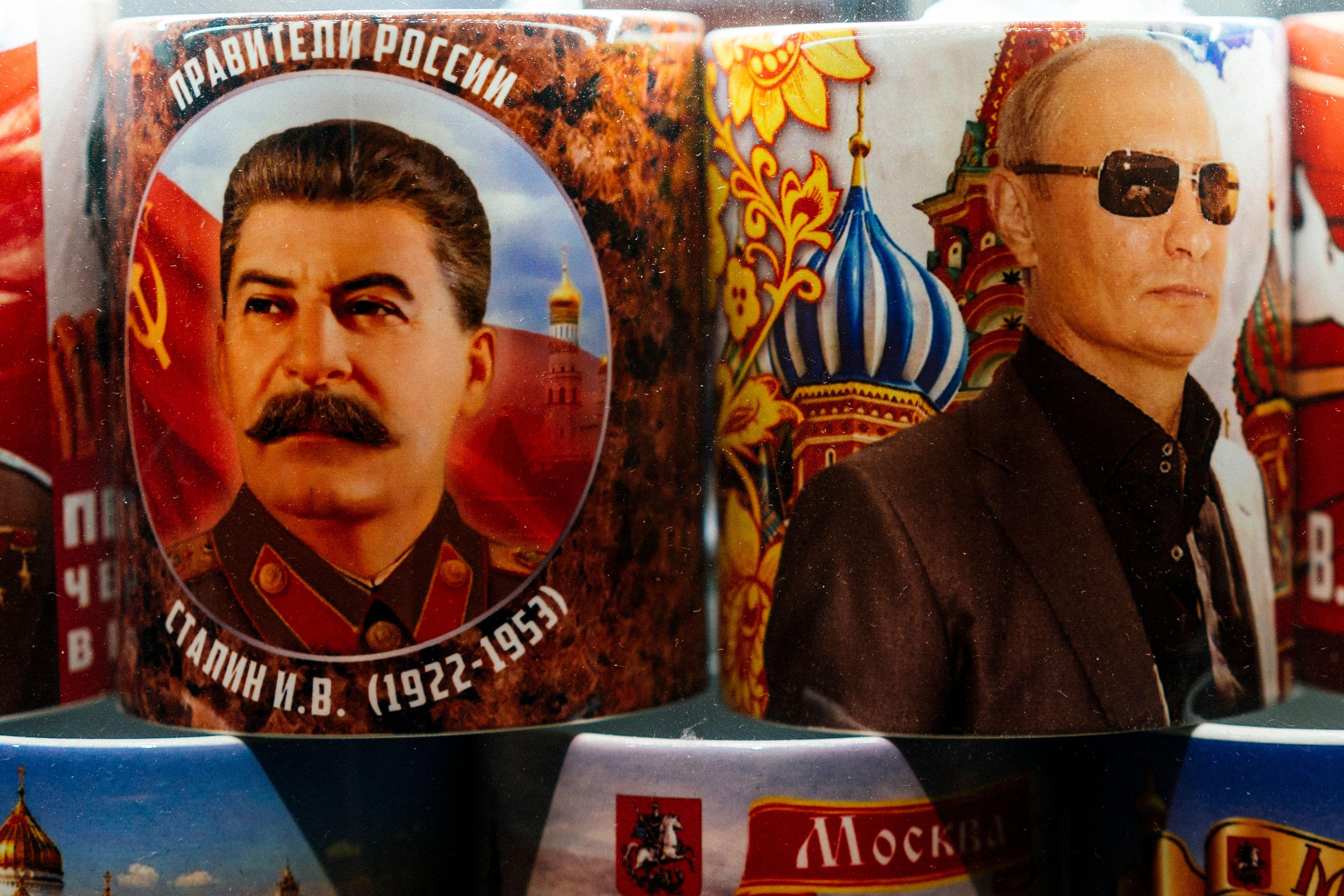 Mugs decorated with images of Stalin and Putin stacked on a shelf