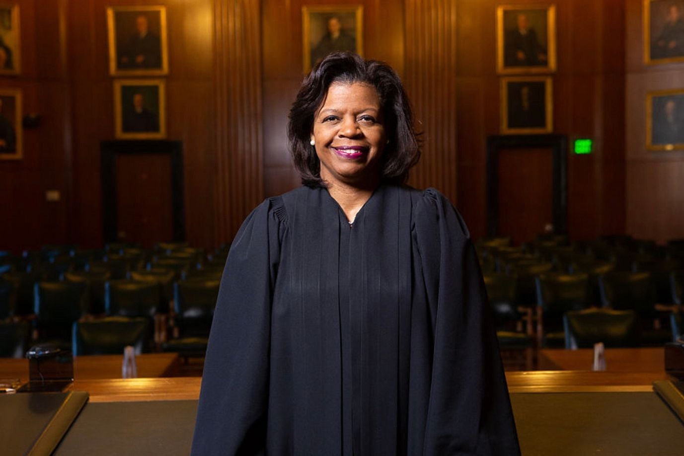 Cheri Beasley smiling in her robes, standing in a courtroom.