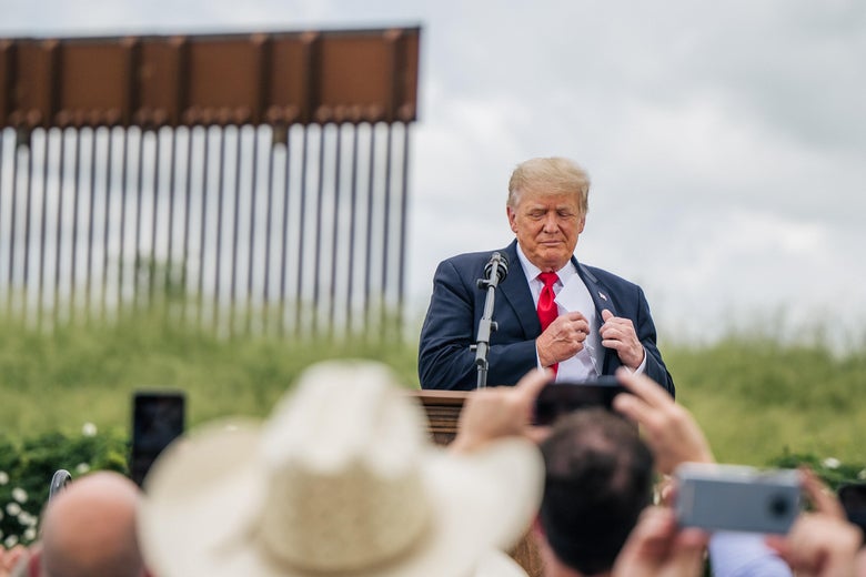 Donald Trump stands in front of a wall at the southern border.