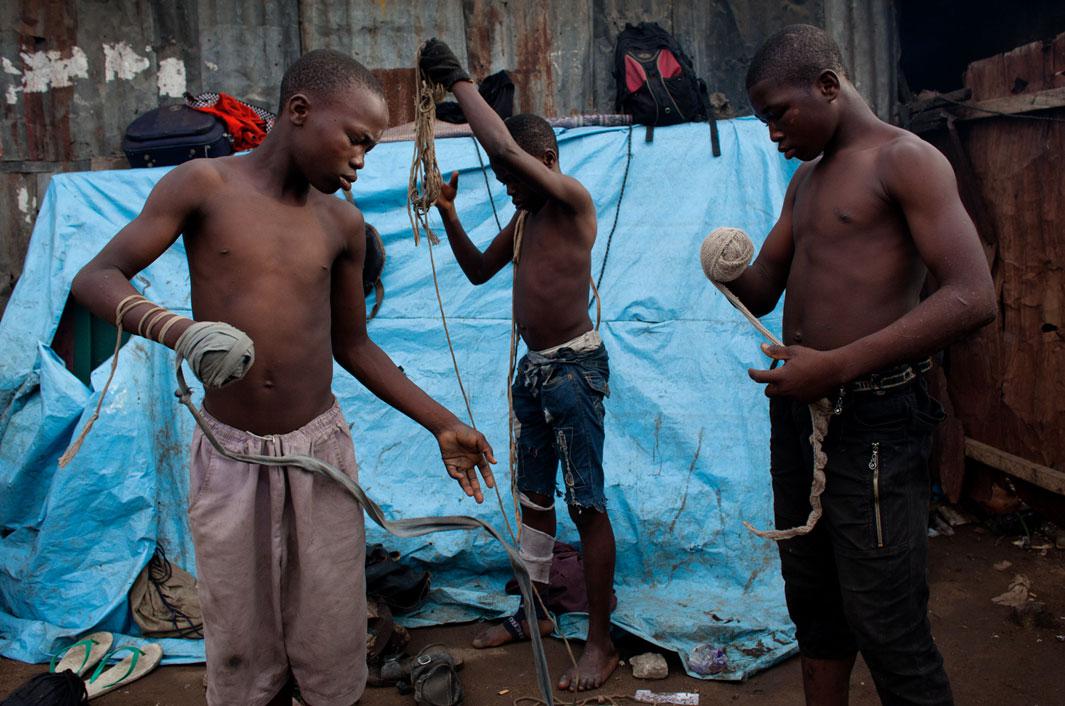 Lagos, Nigeria- Young boxers prepare for their match by tightly wrapping the "spear", or striking arm, with material or rope. If the rope becomes undone during the match, the fight is stopped and the "spear" must be rewrapped before continuing.