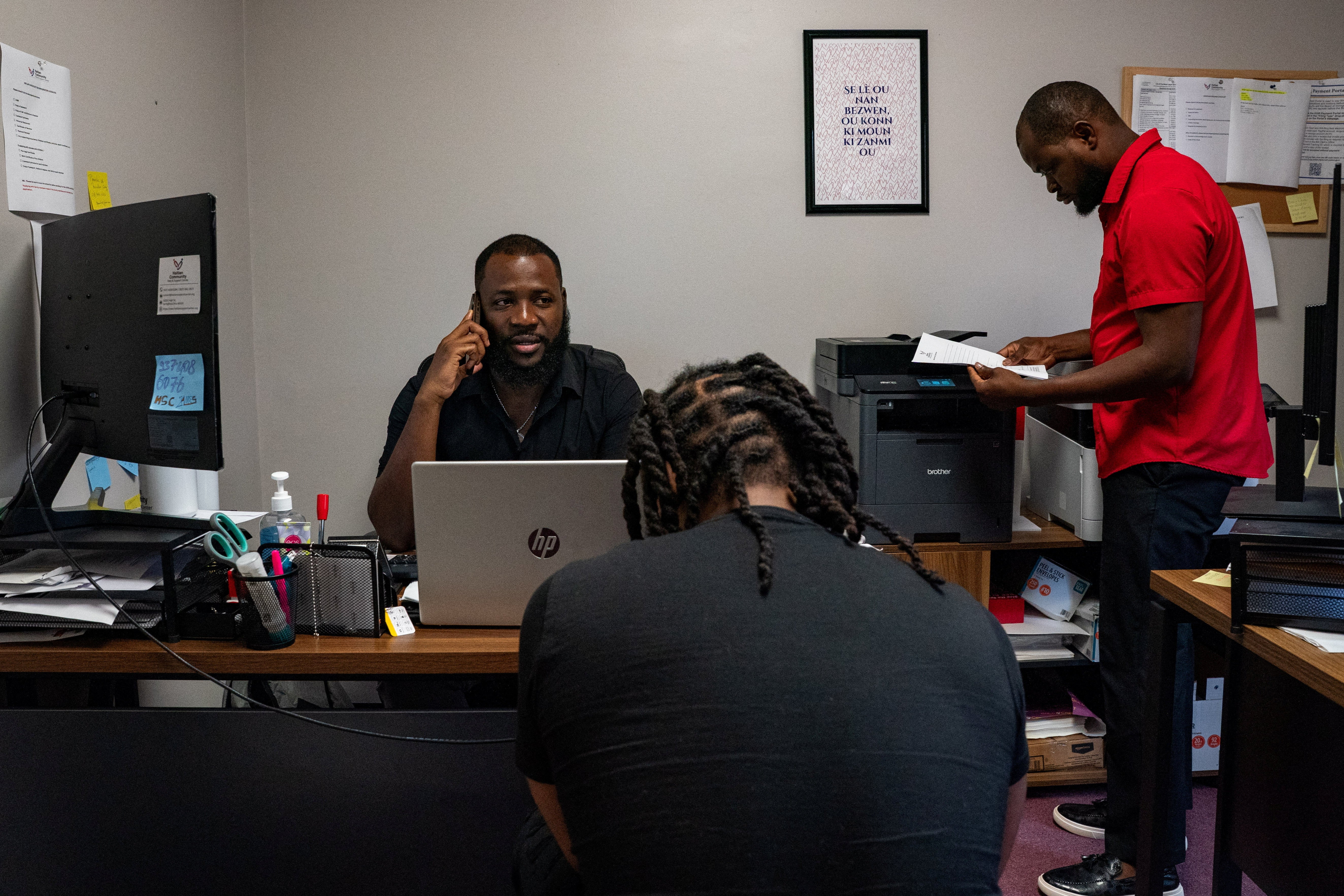 A man sitting in an office, talking on the phone.