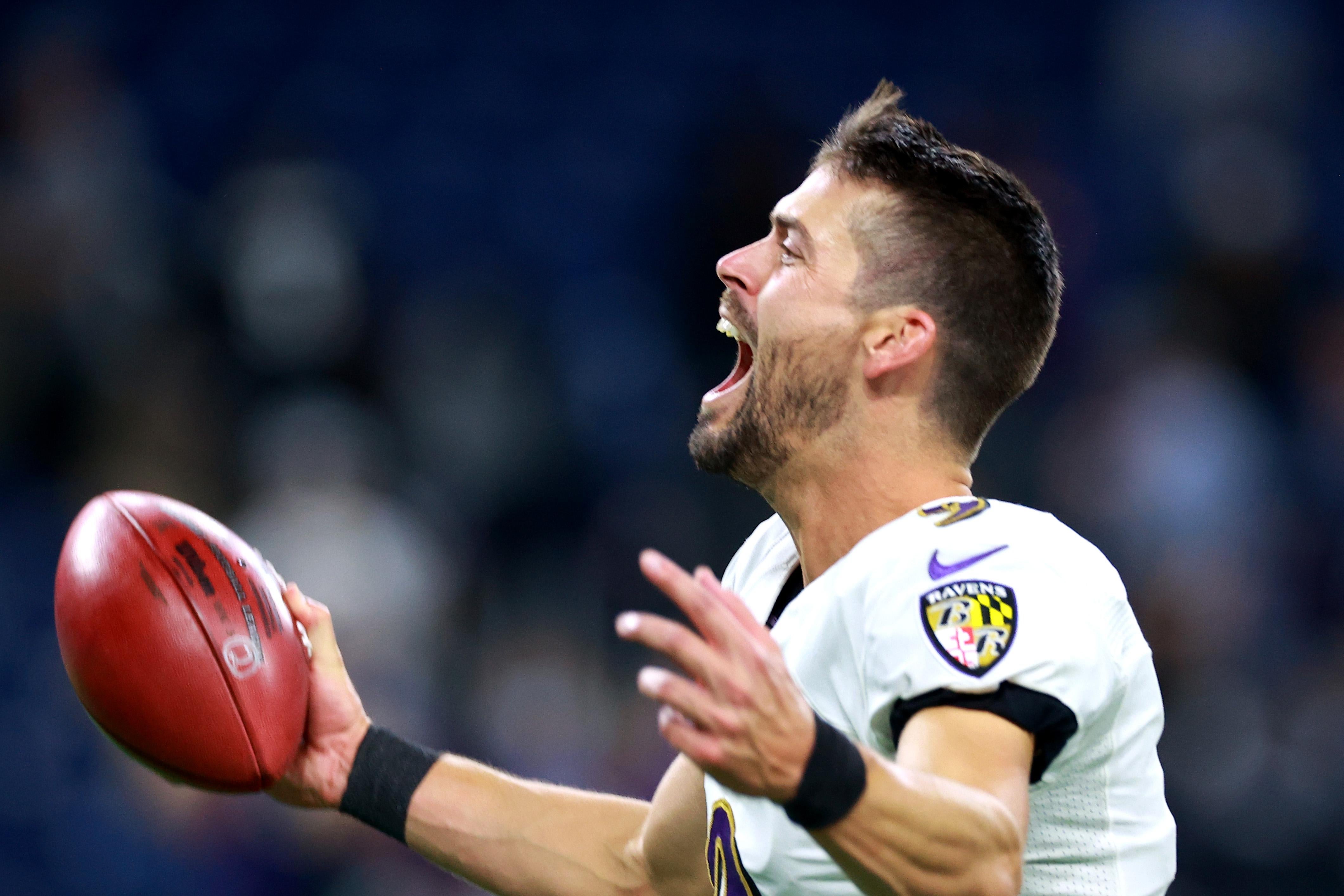 Justin Tucker exults while holding a football.