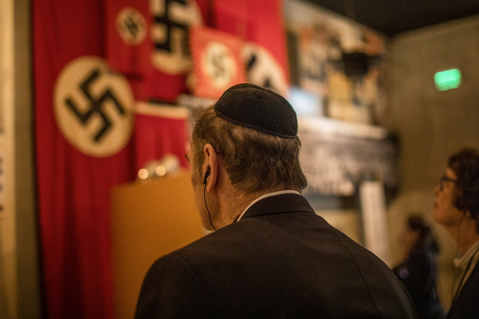 Man in a yamaka hat looks at a Nazi exhibit in Yad Vashem.
