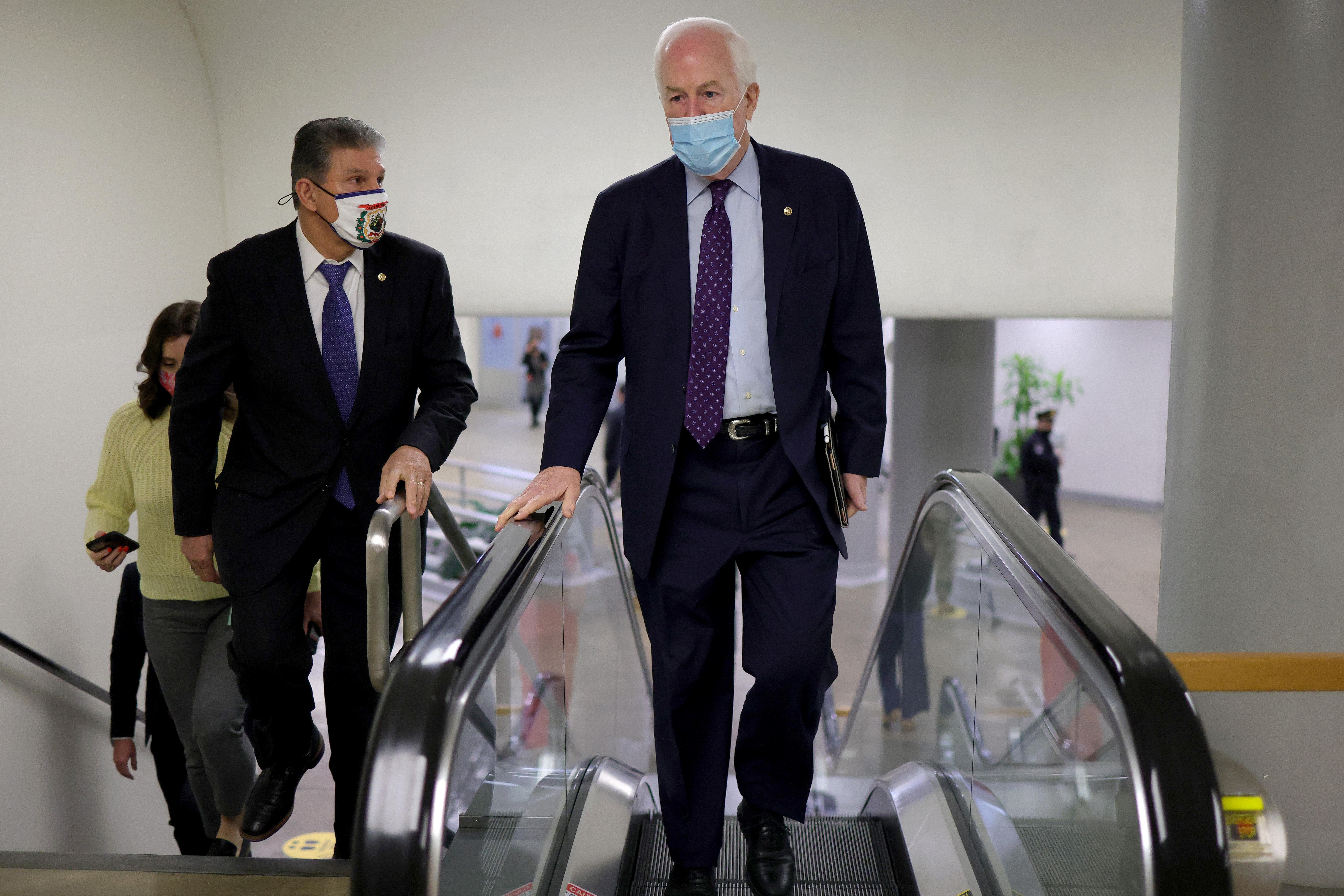John Cornyn walks up an escalator as Joe Manchin walks up the stairs to the U.S. Senate chamber for a vote on March 5