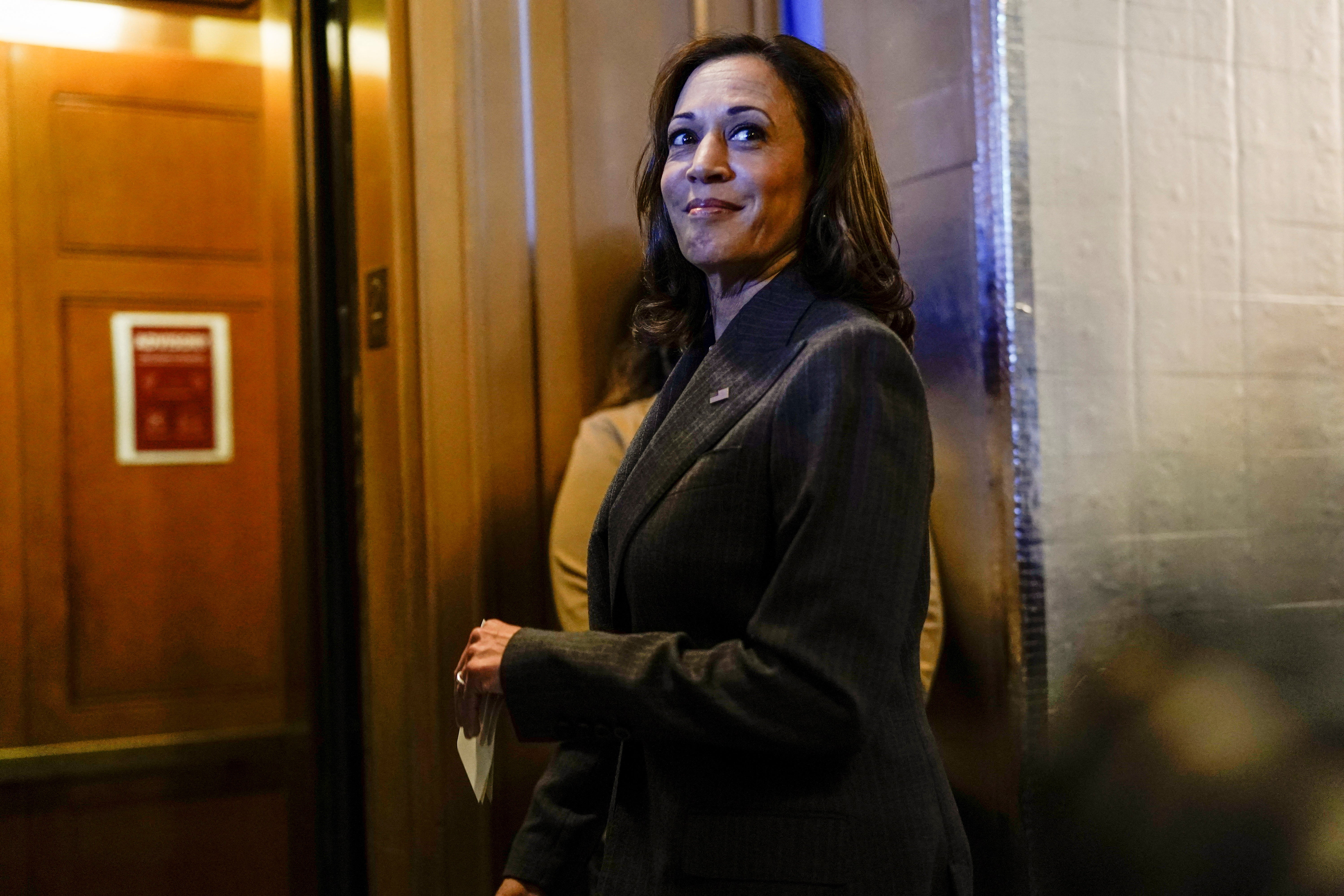 A photo of Kamala Harris, outside of an elevator, smiling slightly; the vice president cast the tie-breaking vote for the "Inflation Reduction Act" that passed on Aug. 7.