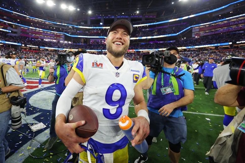 Matthew Stafford smiles and holds a football.