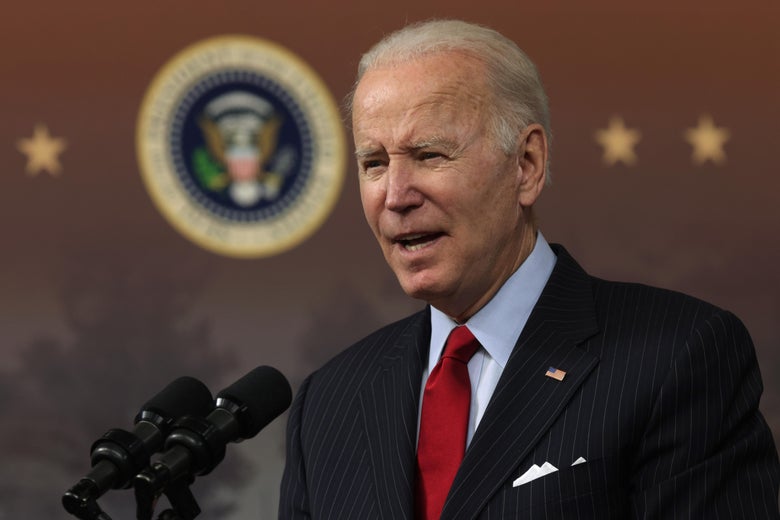 A close-up of Joe Biden speaking into a set of microphones at a podium. 