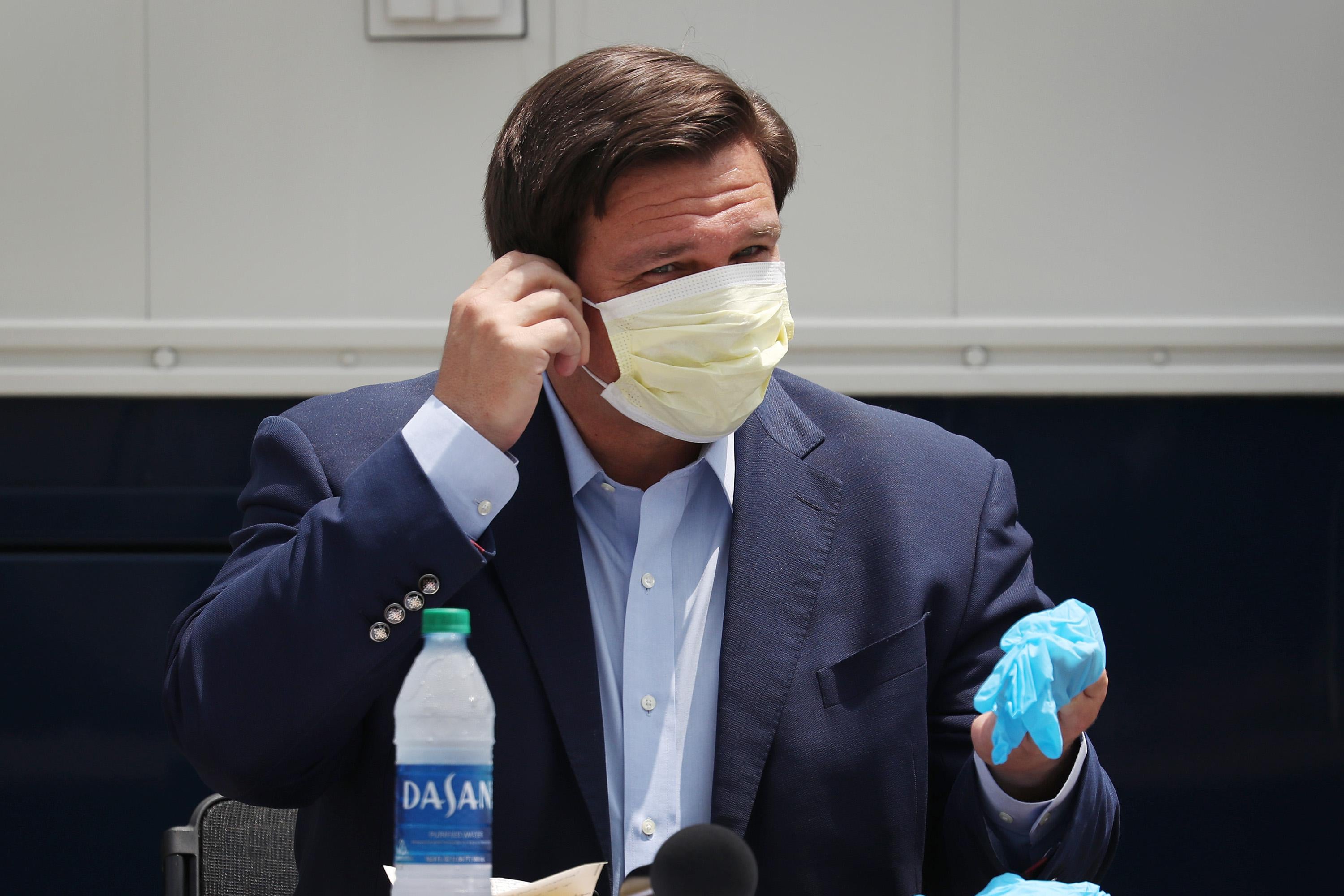 DeSantis wears a mask while speaking at a press conference.