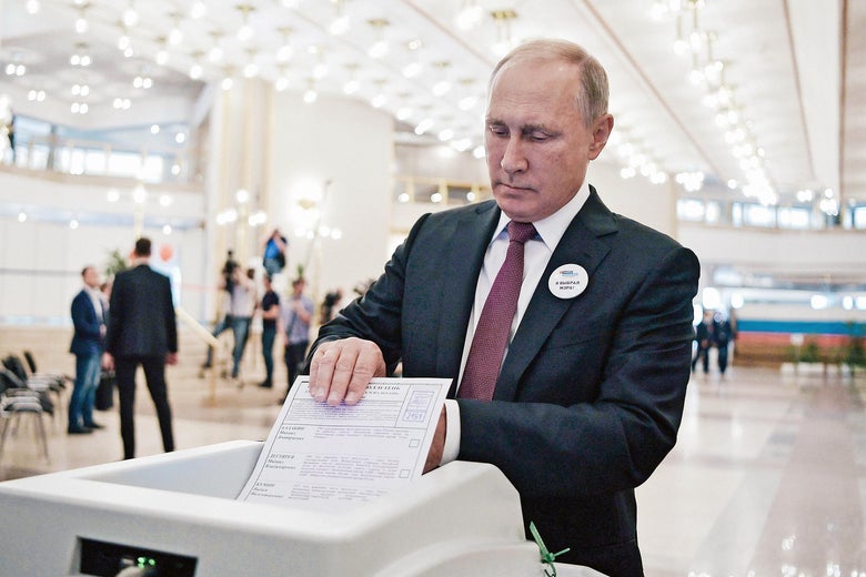 Vladimir Putin puts a ballot into an electronic reader.