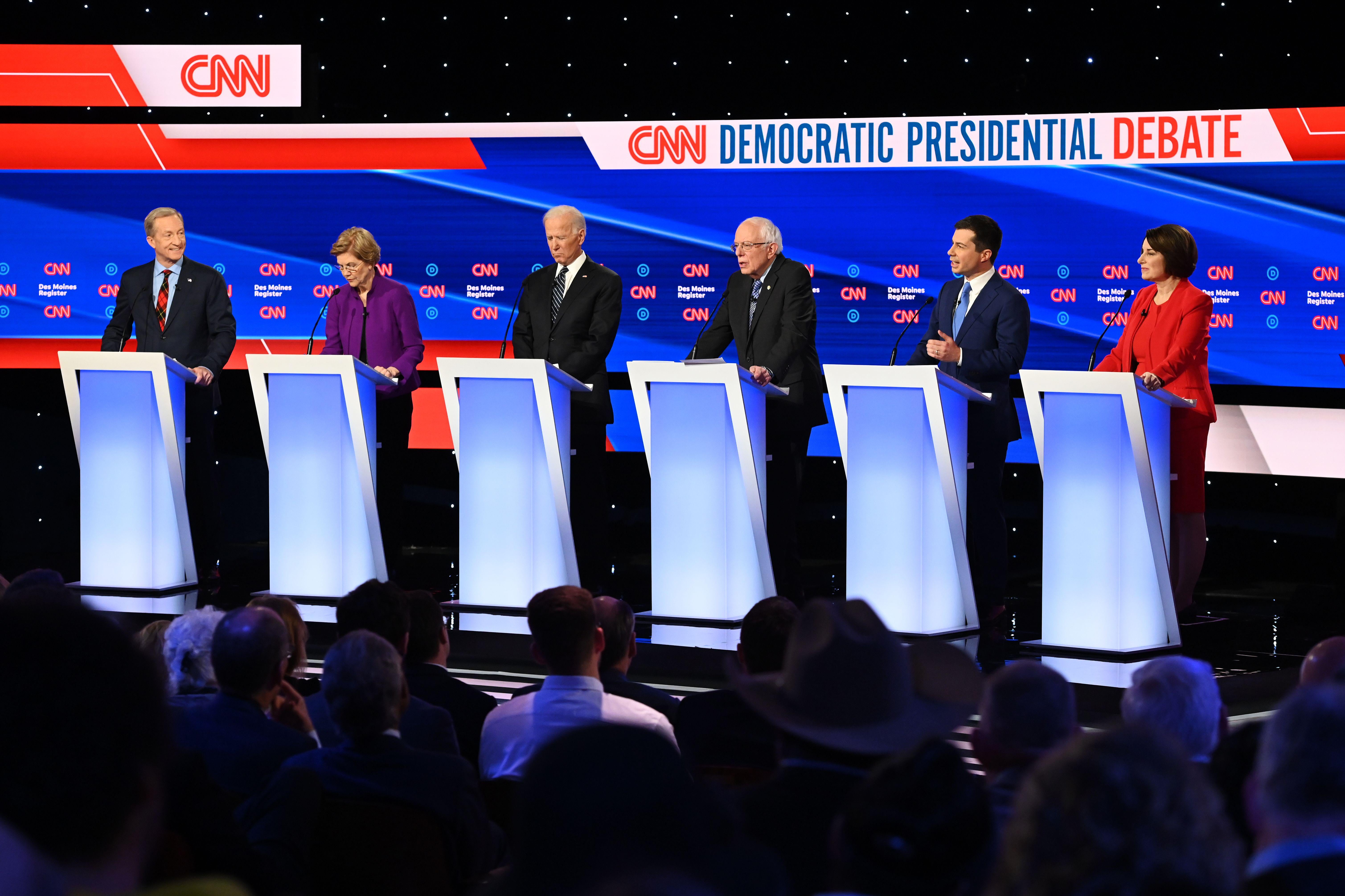The Democratic candidates stand behind podiums on the debate stage.