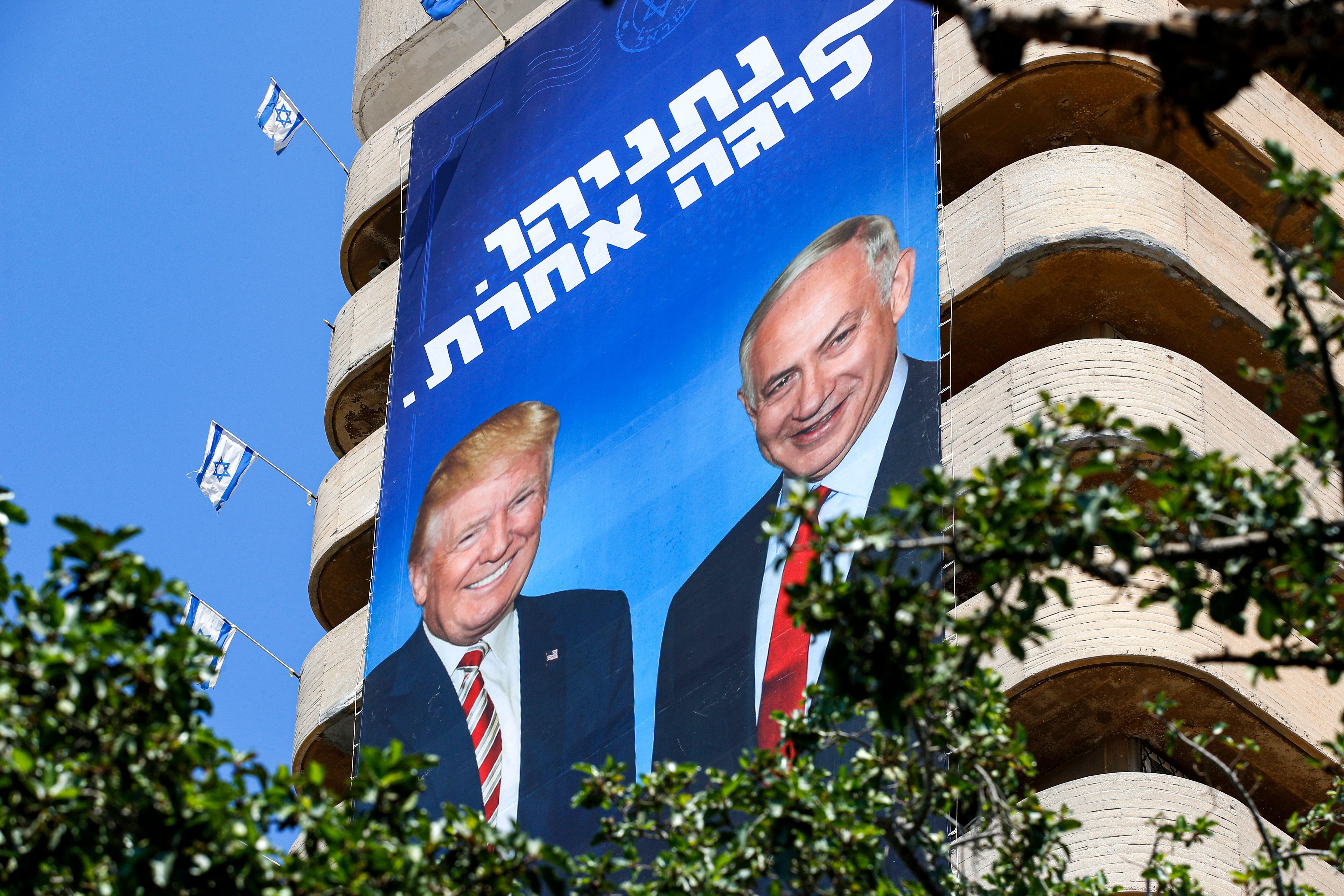 A giant Israeli Likud party election banner hanging from a building shows Benjamin Netanyahu with Donald Trump.