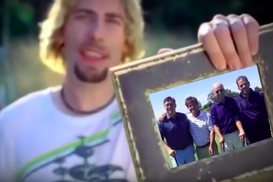 A blurry Chad Kroeger holds a picture frame with an image of four people in it. Two of them are Joe and Hunter Biden.