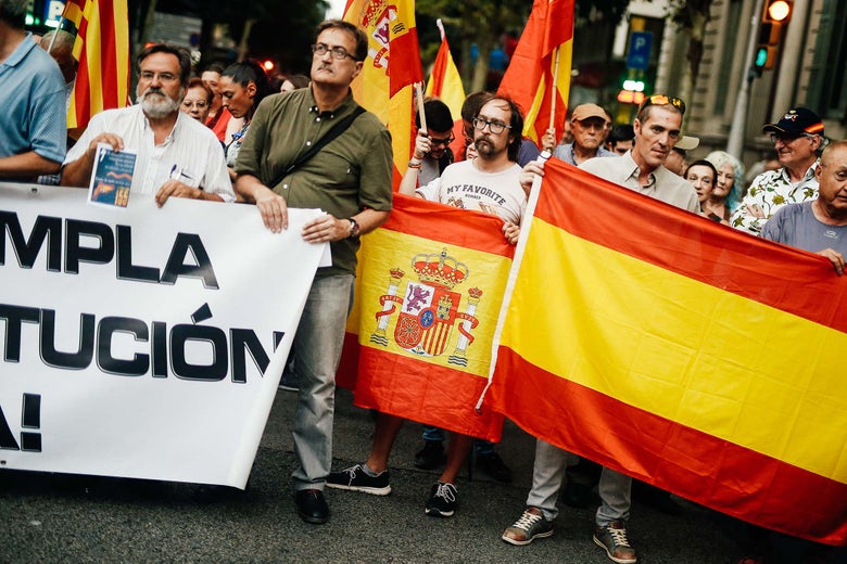 Men hold Spanish flags, signs, and a banner.