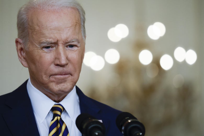 Biden speaking at a podium with his eyes downcast