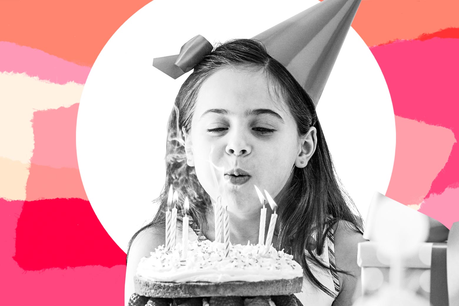 A girl in a party hat blows out candles on a cake.