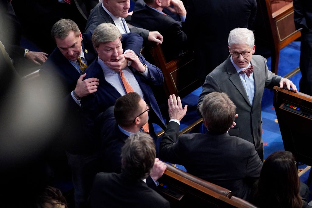 An overhead view of Rogers being restrained as others around him are caught in mid-reaction to the incident.