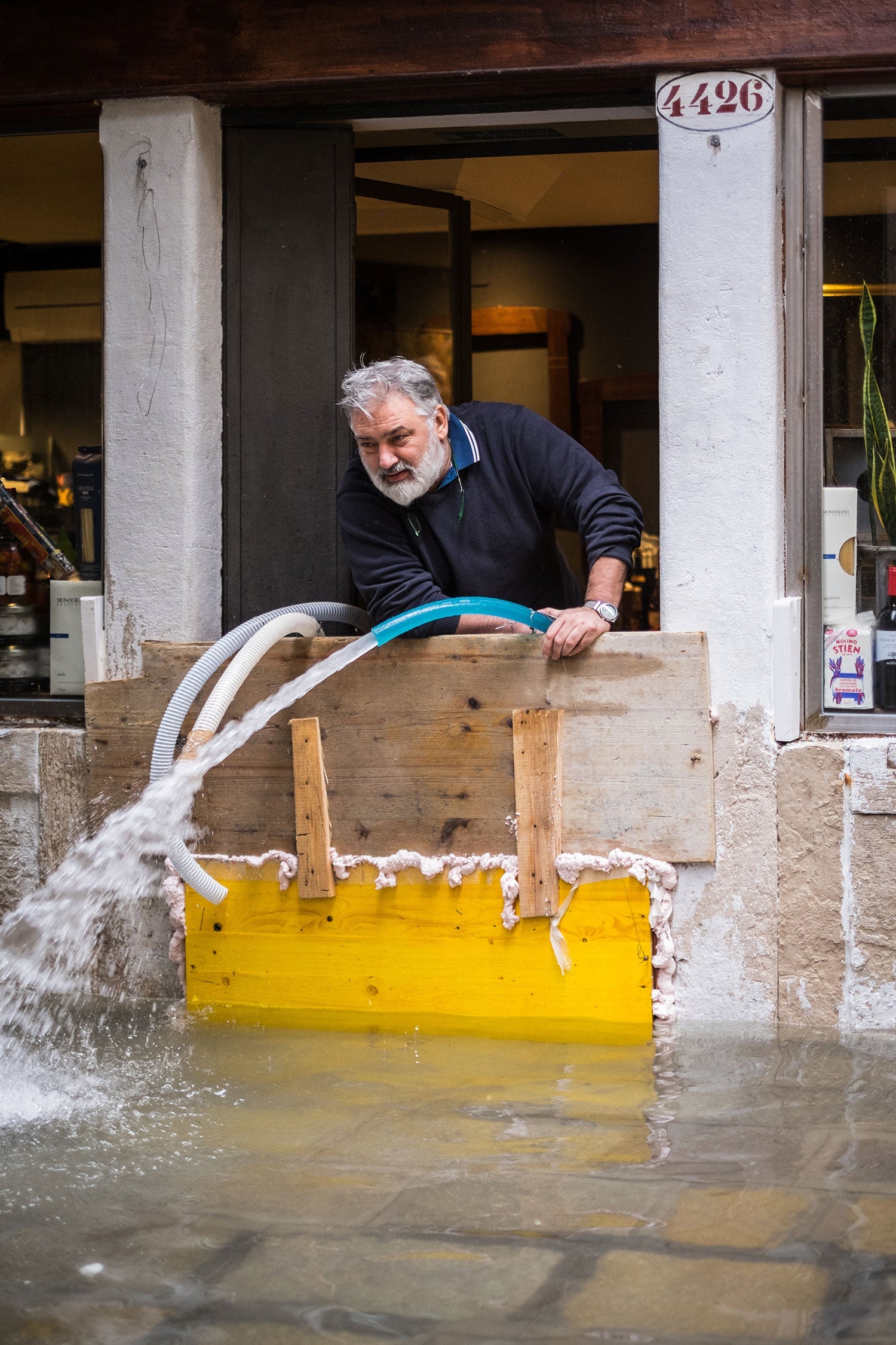 A man pumping water out of his flooded restaurant in Venice.