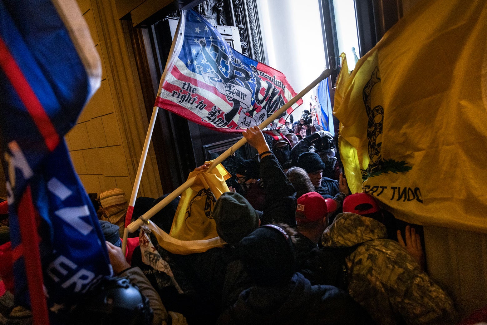 Rioters waving Trump and MAGA and Gadsden flags breach the Capitol doorways.