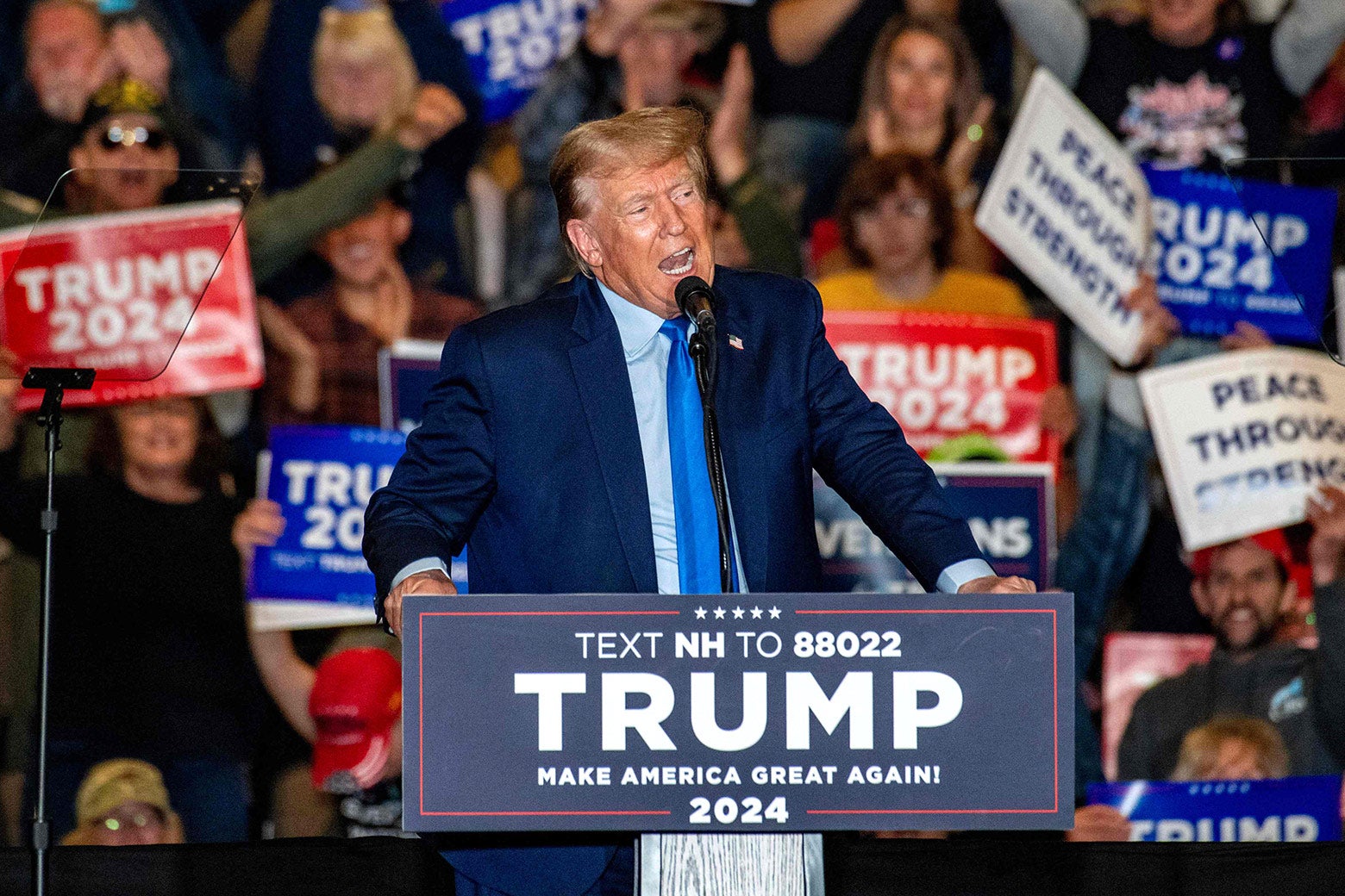 Trump in front of a MAGA podium with a text donation number.