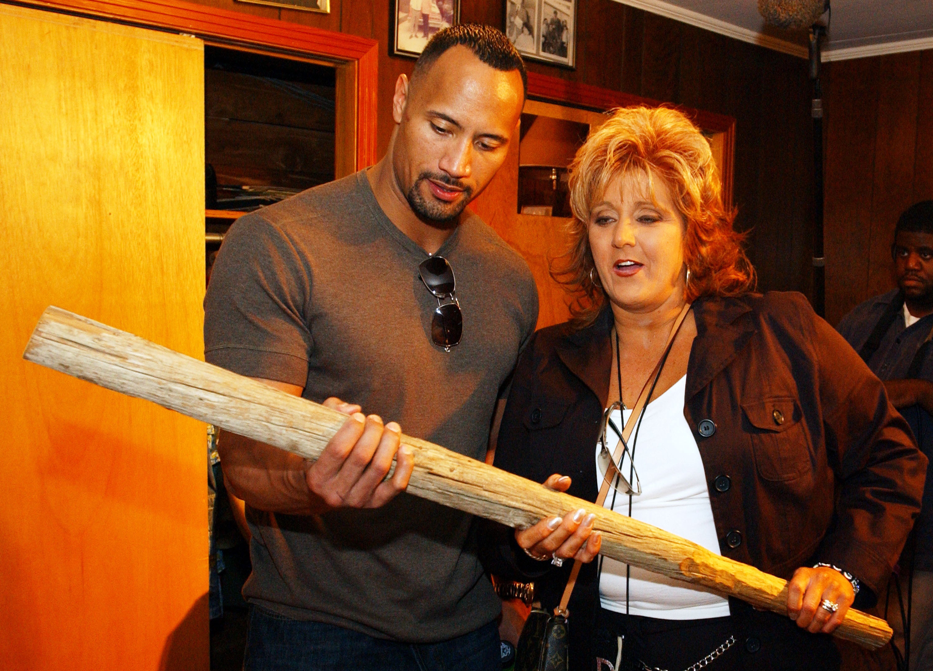 The Rock and a middle-aged woman with blond hair holding a wood bat.