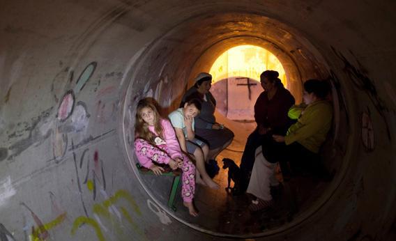 Israelis take cover in a large concrete pipe used as a bomb shelter.