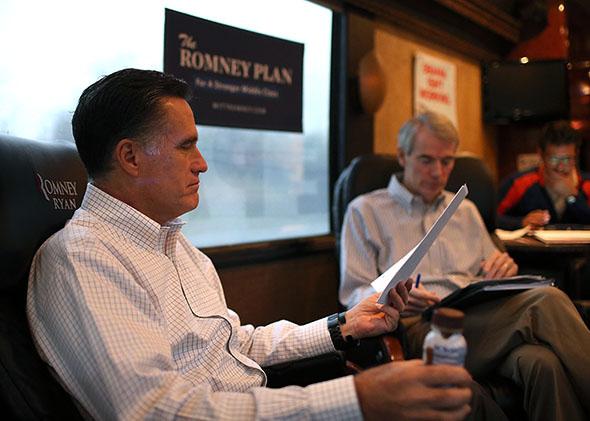 Mitt Romney looks over documents with campaign adviser Sen. Rob Portman on his campaign bus en on Oct. 29, 2012 in Avon Lake, Ohio. 