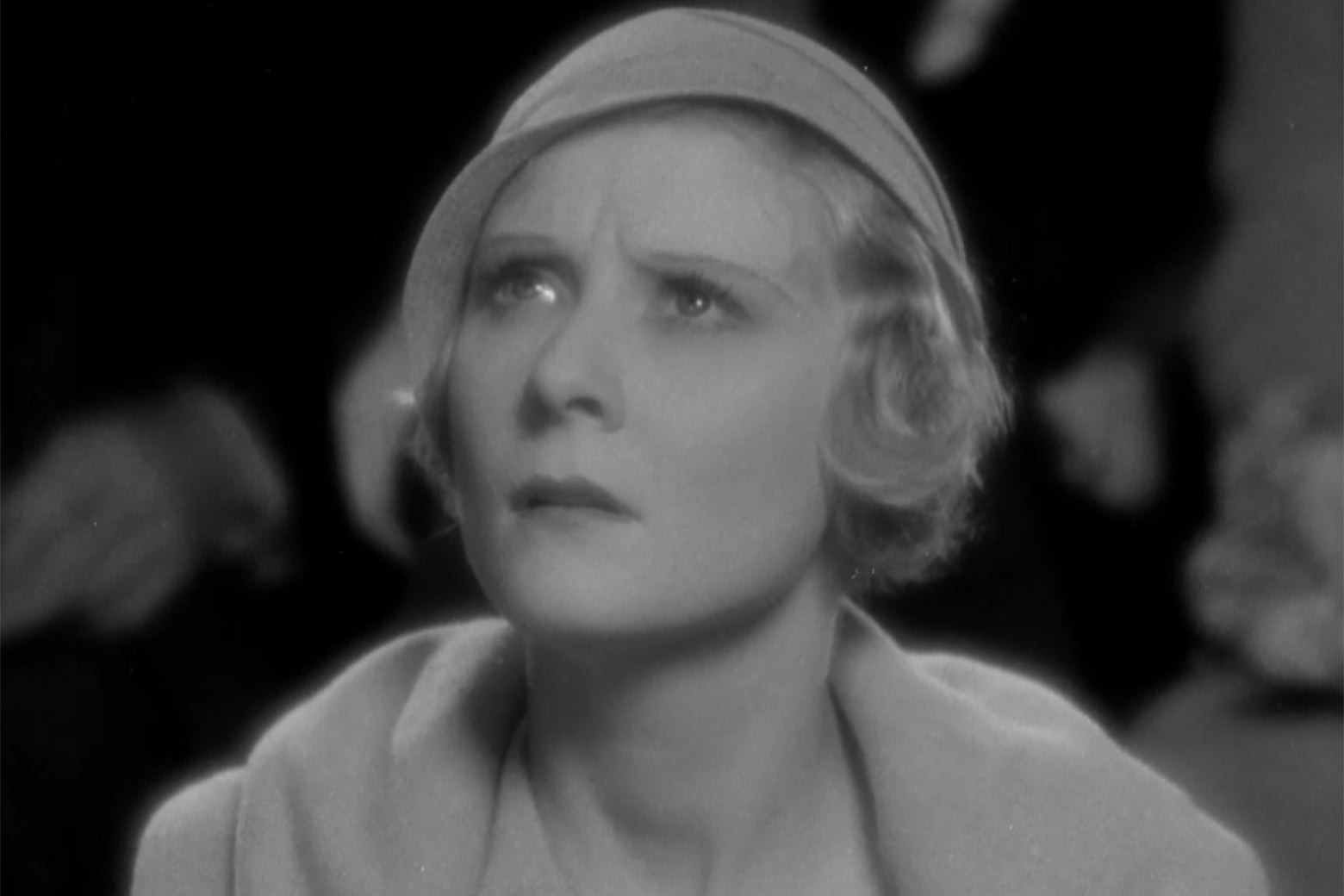 Actress Peg Entwistle, in a cloche hat and matching jacket, looking concerned.