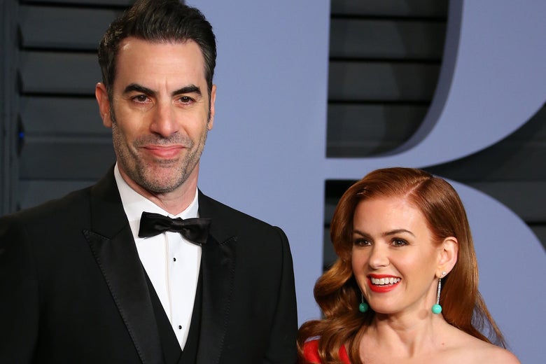 Sacha Baron Cohen and Isla Fisher on a red carpet. He is a head taller than she is.