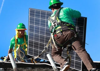 Ведущие установщики для SolarCity, Charles Groves, Right и Matt Parra, установите солнечные батареи на крыше дома 31 марта 2011 года в Пало -Альто, Калифорния