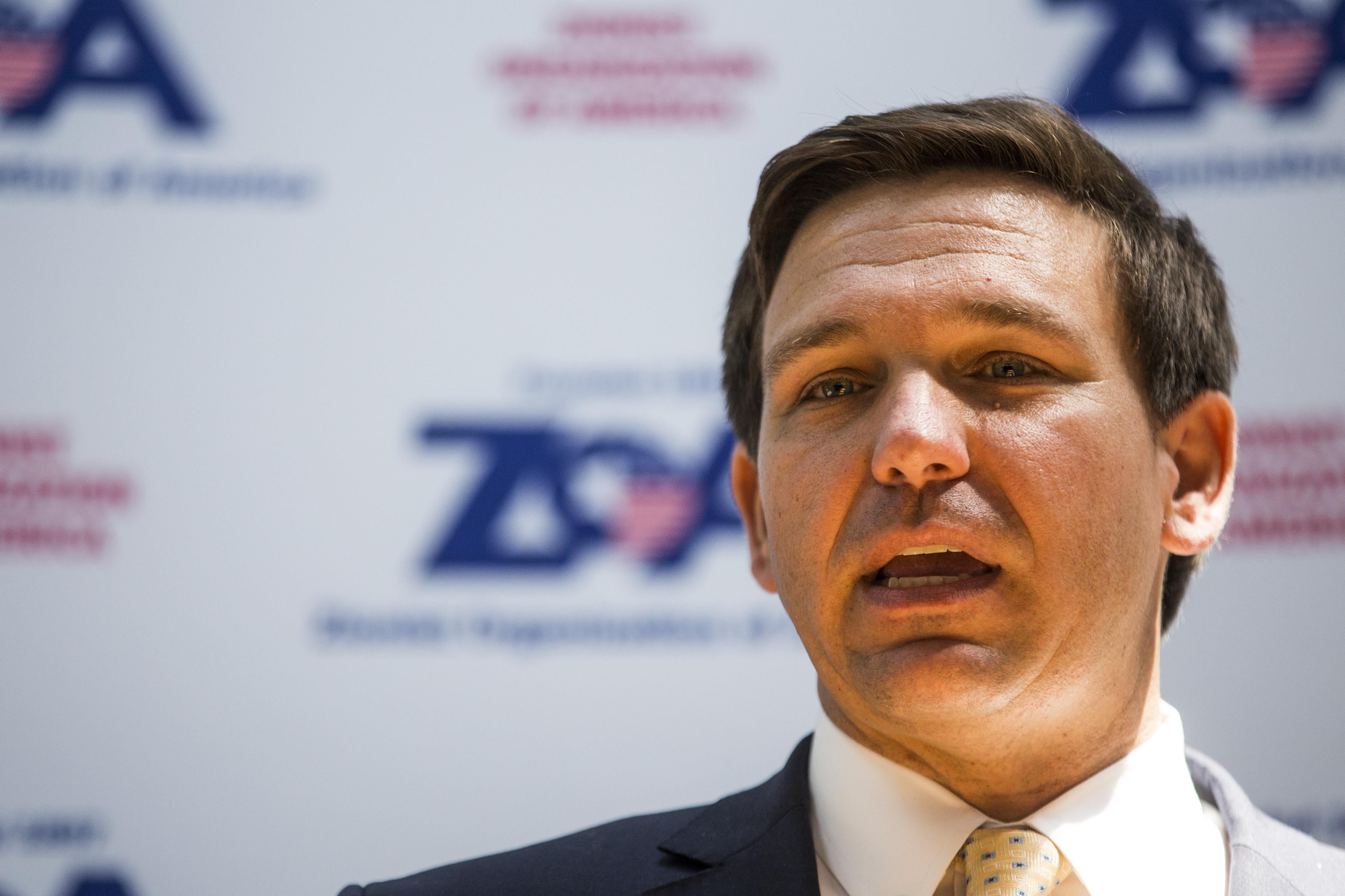 Florida Rep. Ron DeSantis speaking in front of a banner for the Zionist Organization of America.