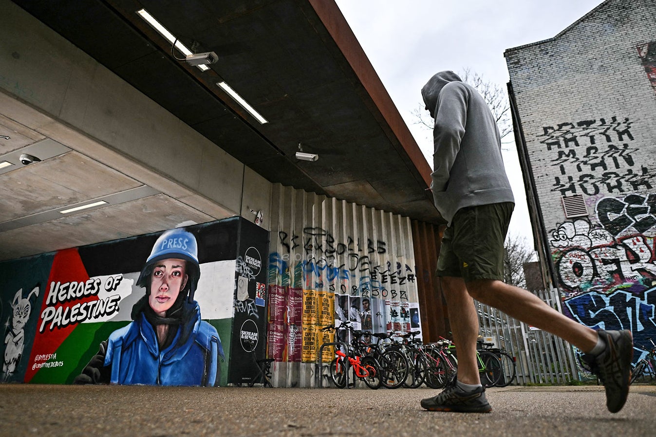 Eine Person geht vor einem Graffiti-Wandbild vorbei, auf dem steht
