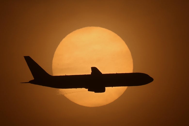 A silhouette of a plane seen against the sun