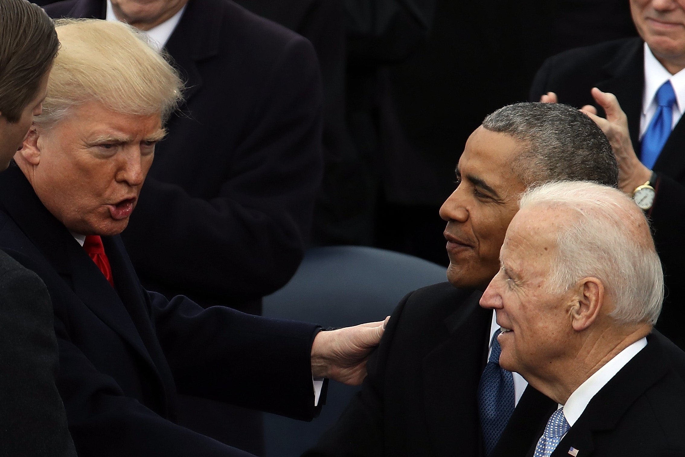 Trump gestures as Biden and Obama look on.