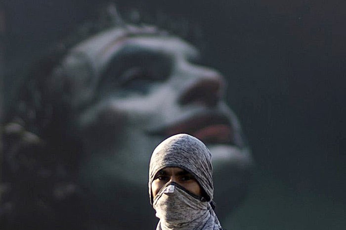 A Chilean protester stands in front of a mural of the Joker.