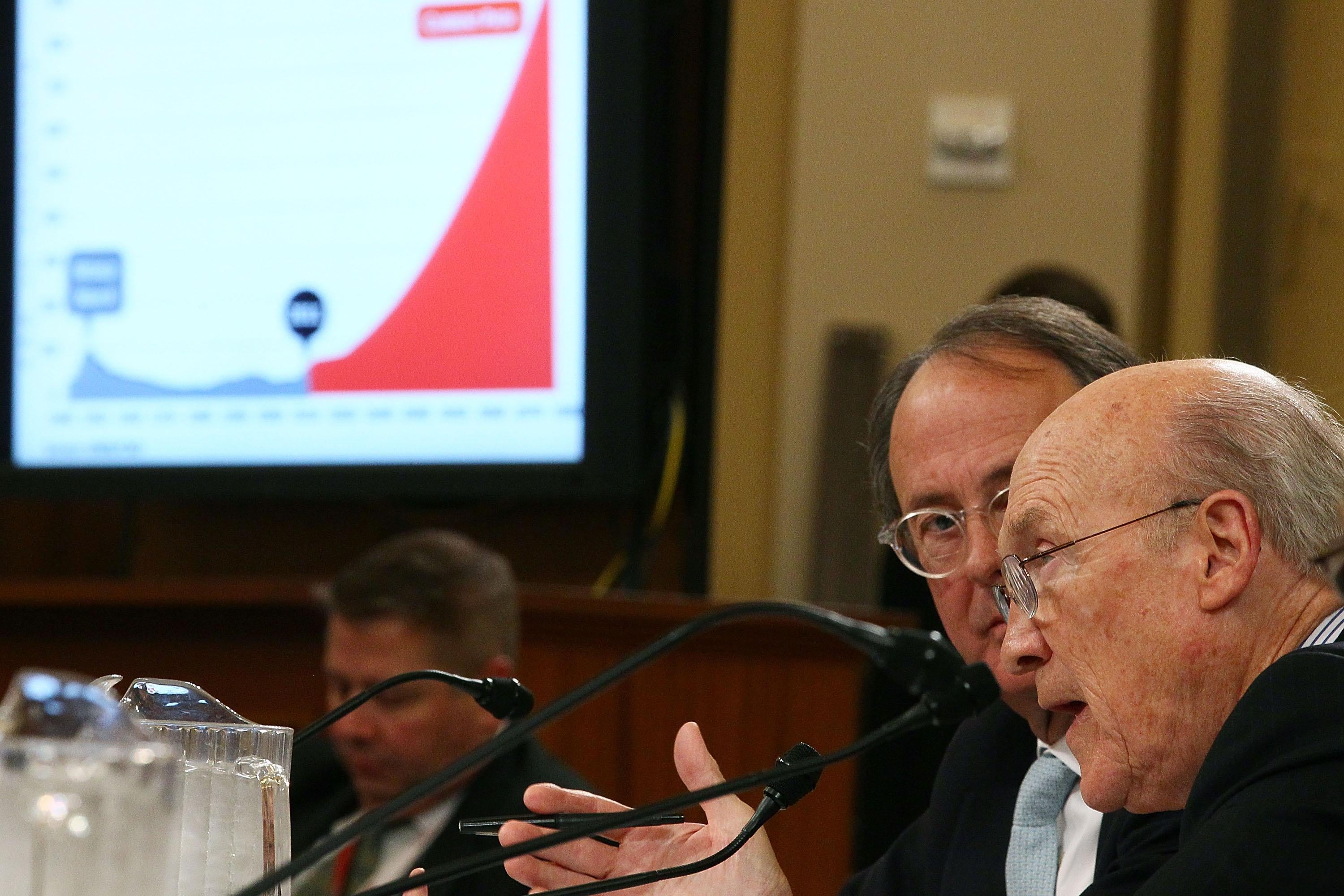 Simpson and Bowles are seated in a Joint Deficit Reduction Committee hearing on Capitol Hill on Nov. 1, 2011. A chart is projected on the screen nearby.