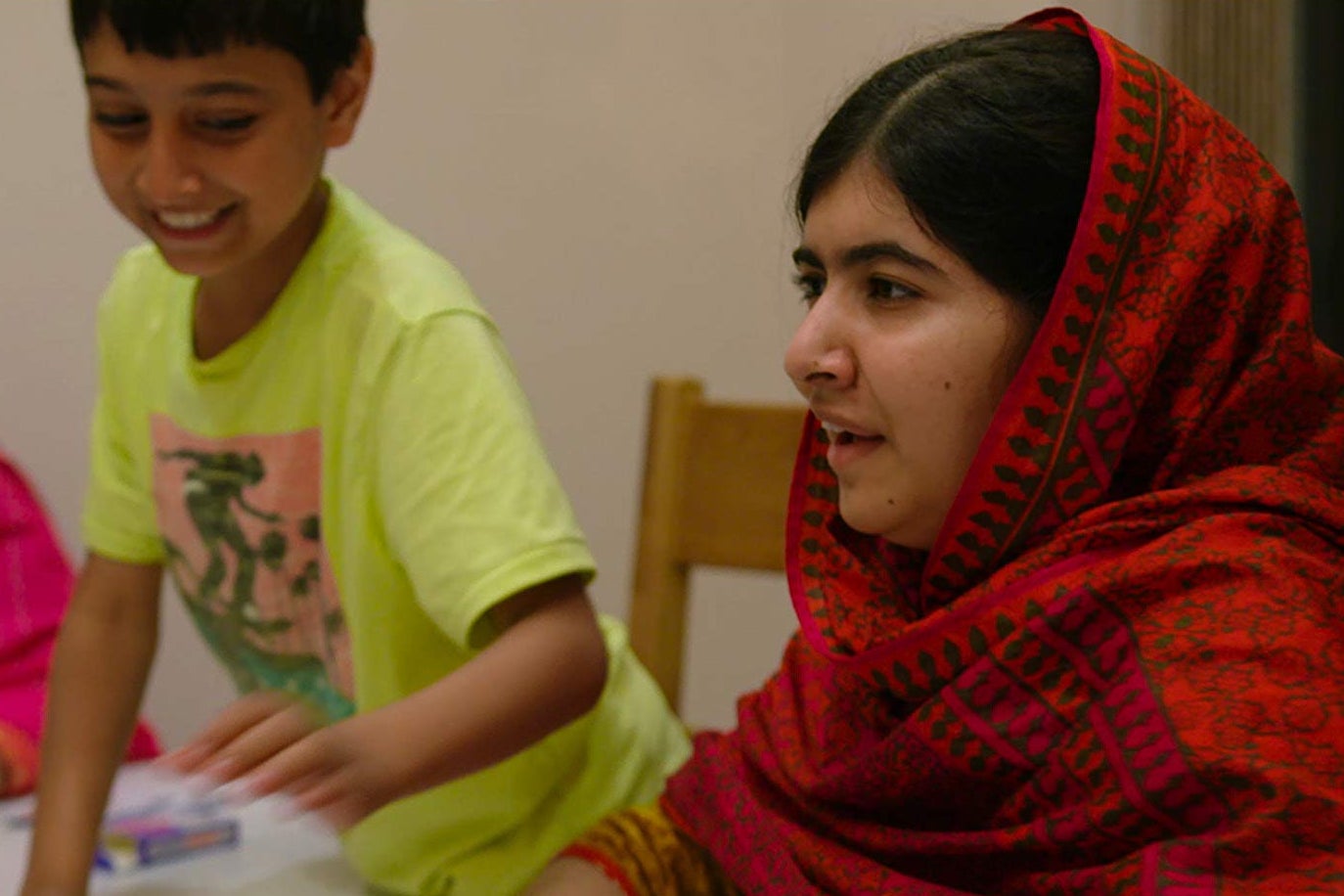 Malala Yousafzai. In the background, a young boy smiles.