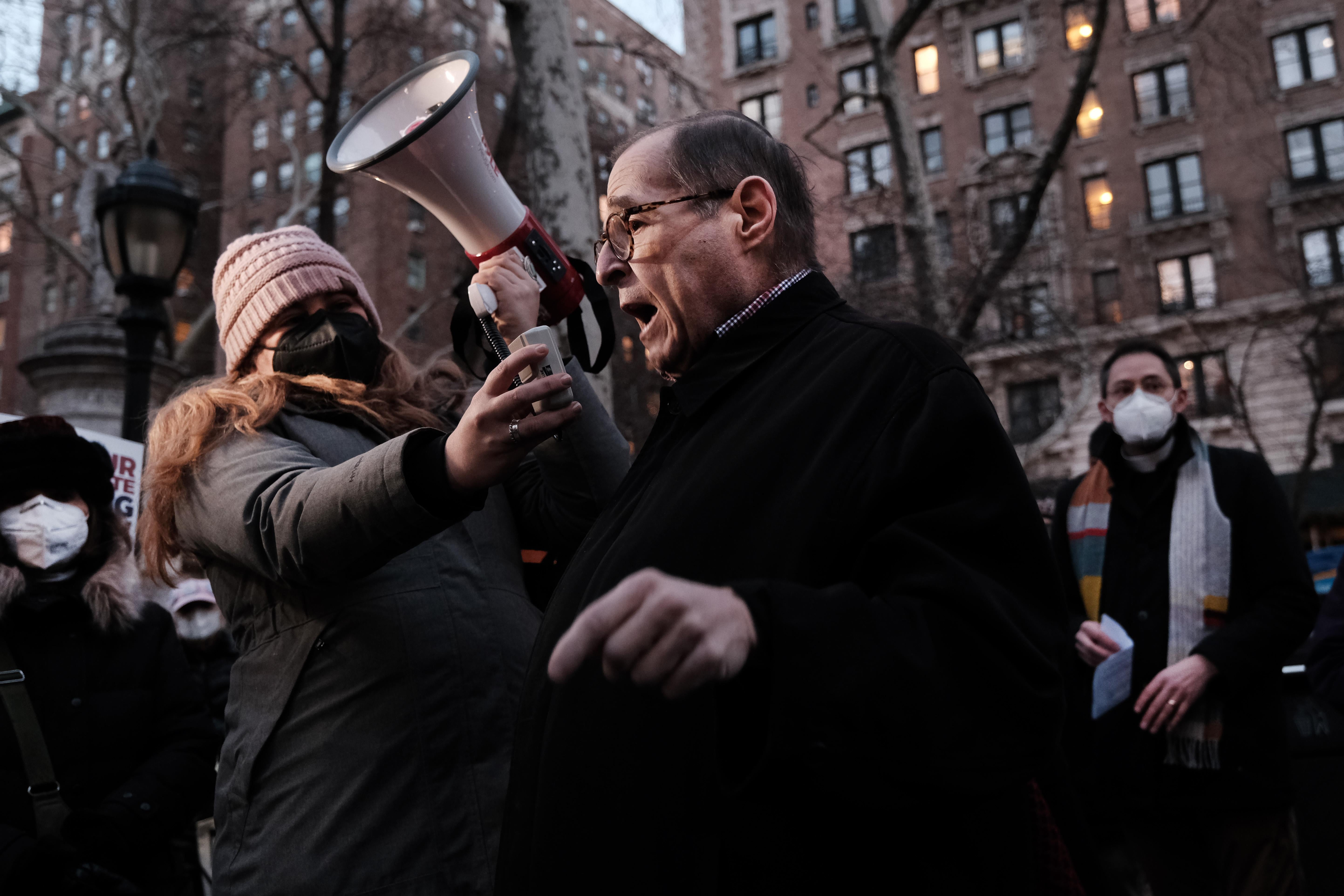Nadler speaks into a bullhorn being held by someone else, who is wearing a mask.